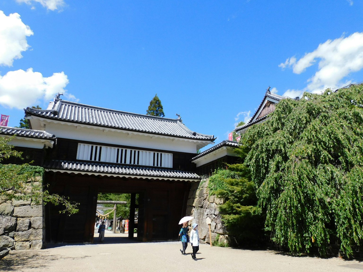 Puerta japonesa tradicional bajo un cielo azul con exuberante vegetación