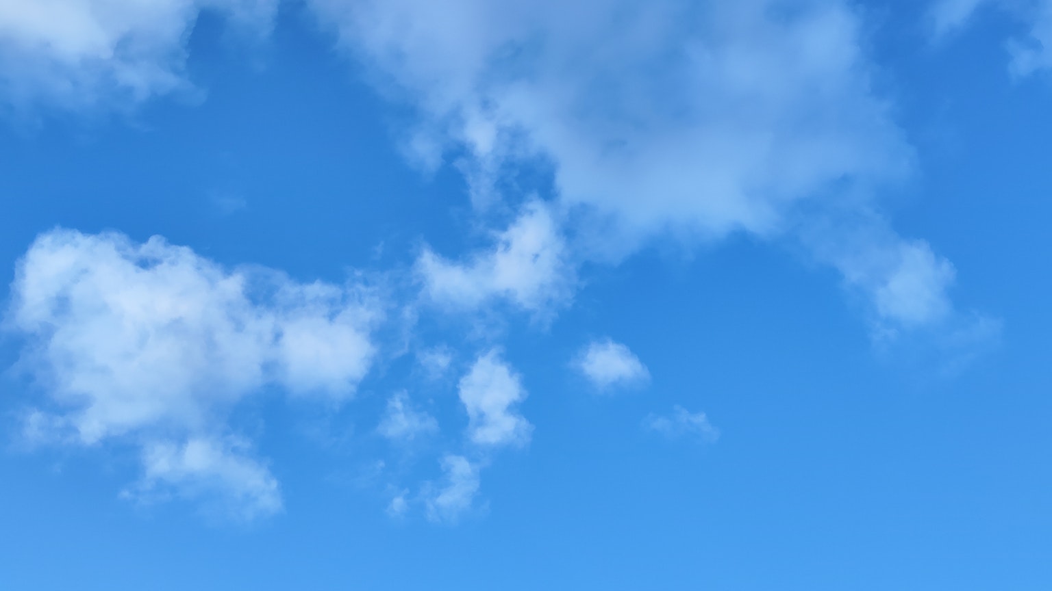 A bright blue sky with fluffy white clouds