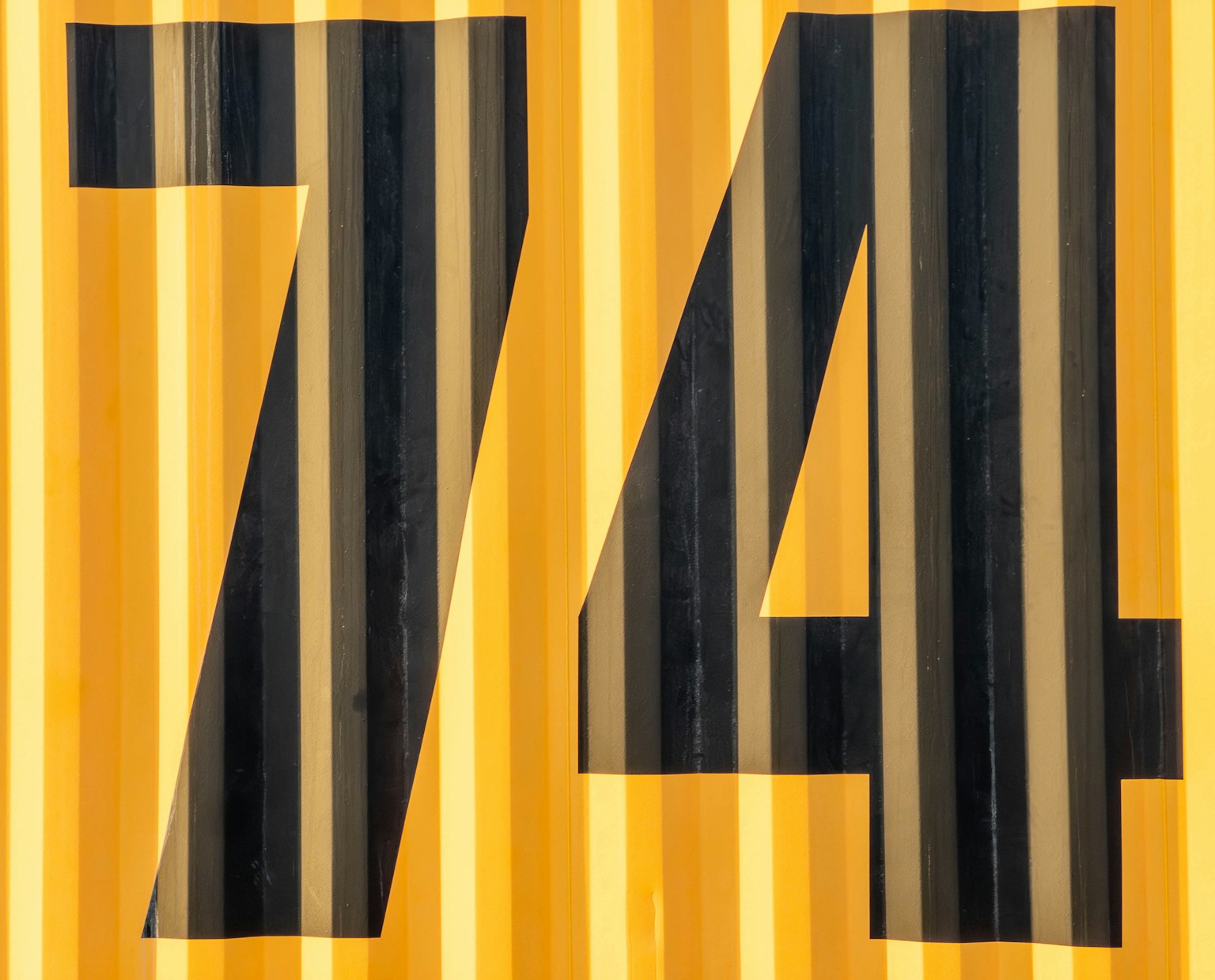 Grand chiffre noir 74 sur un fond rayé jaune
