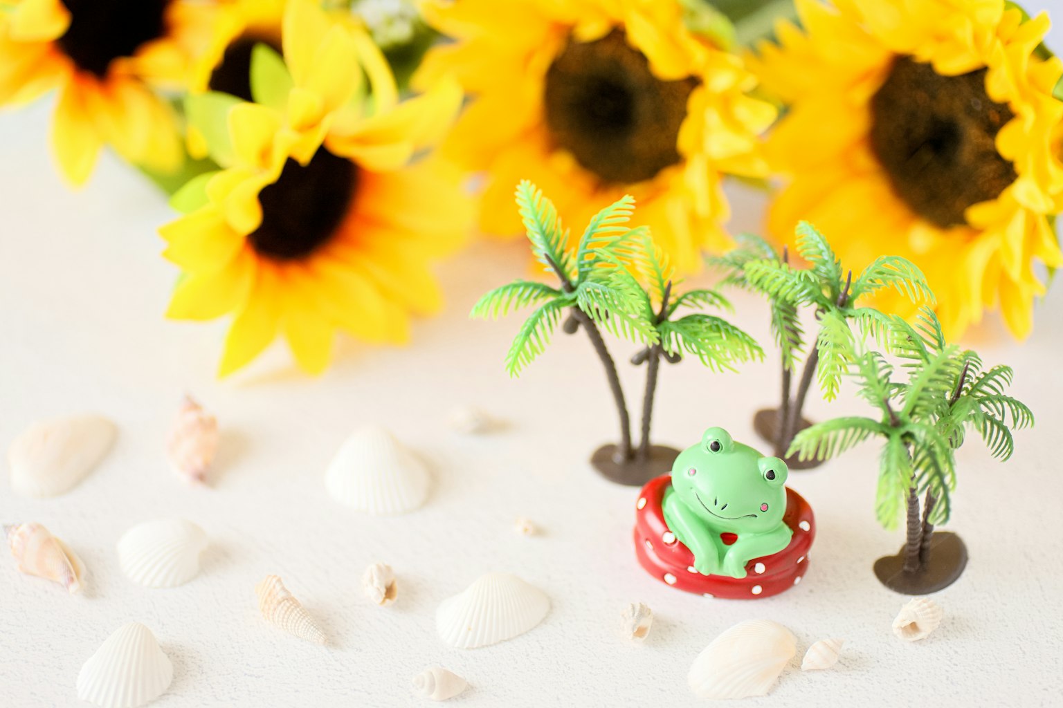 Bunte Szene mit Sonnenblumen und Stranddekorationen mit einer Froschfigur
