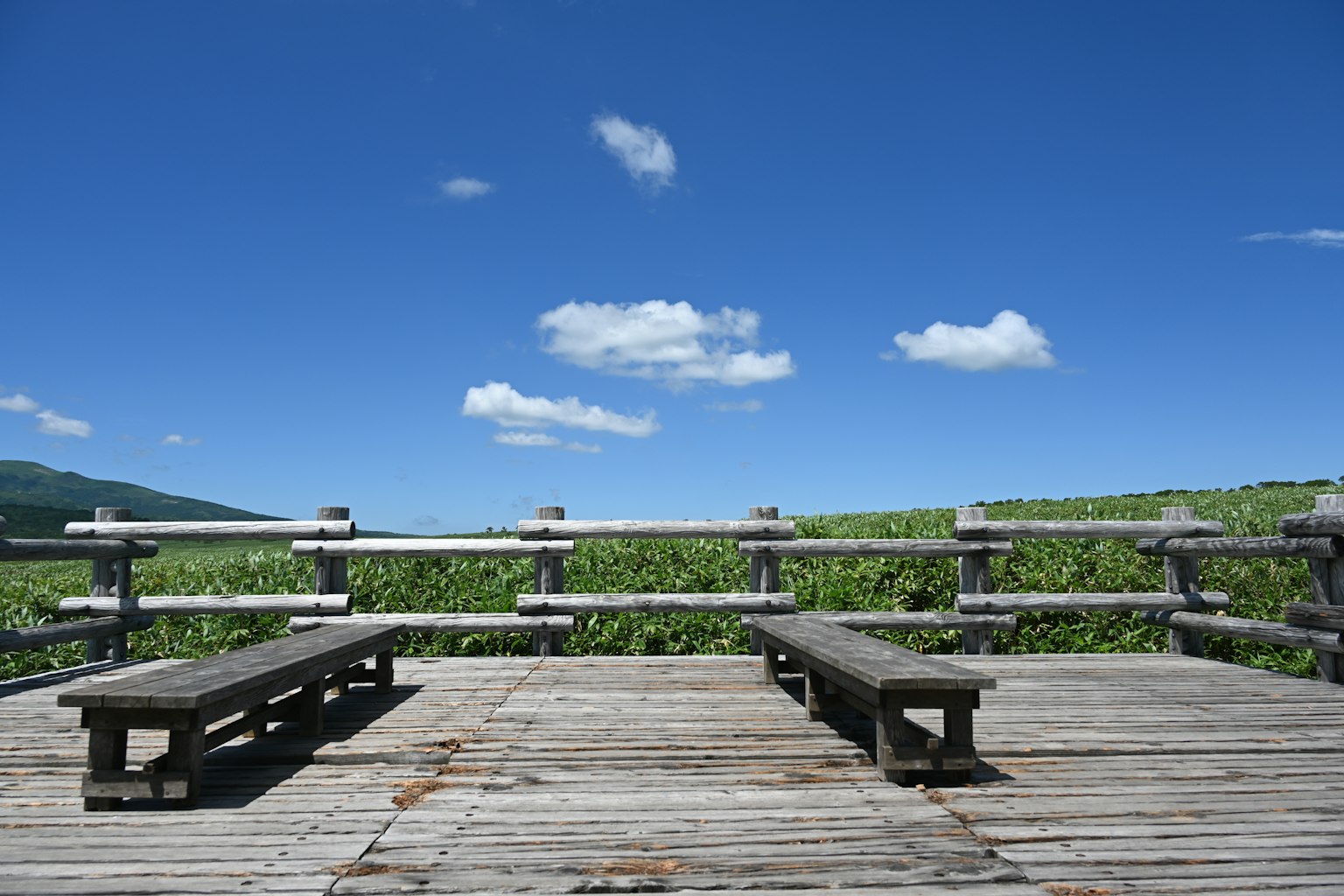 Wooden deck with two benches under a clear blue sky