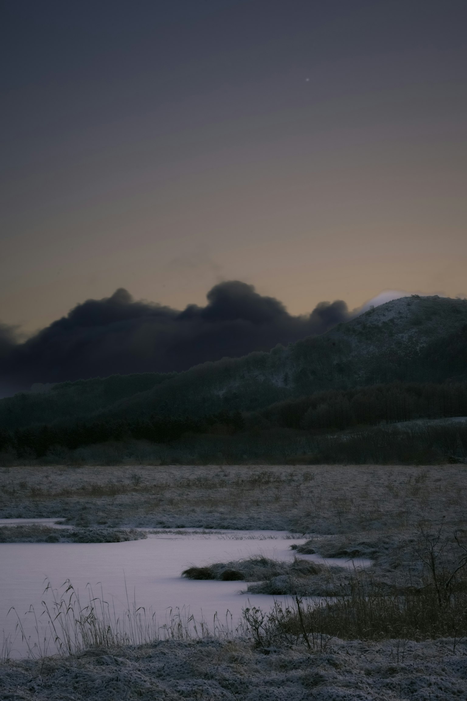 Paesaggio invernale sereno con neve e montagne silhouette al crepuscolo
