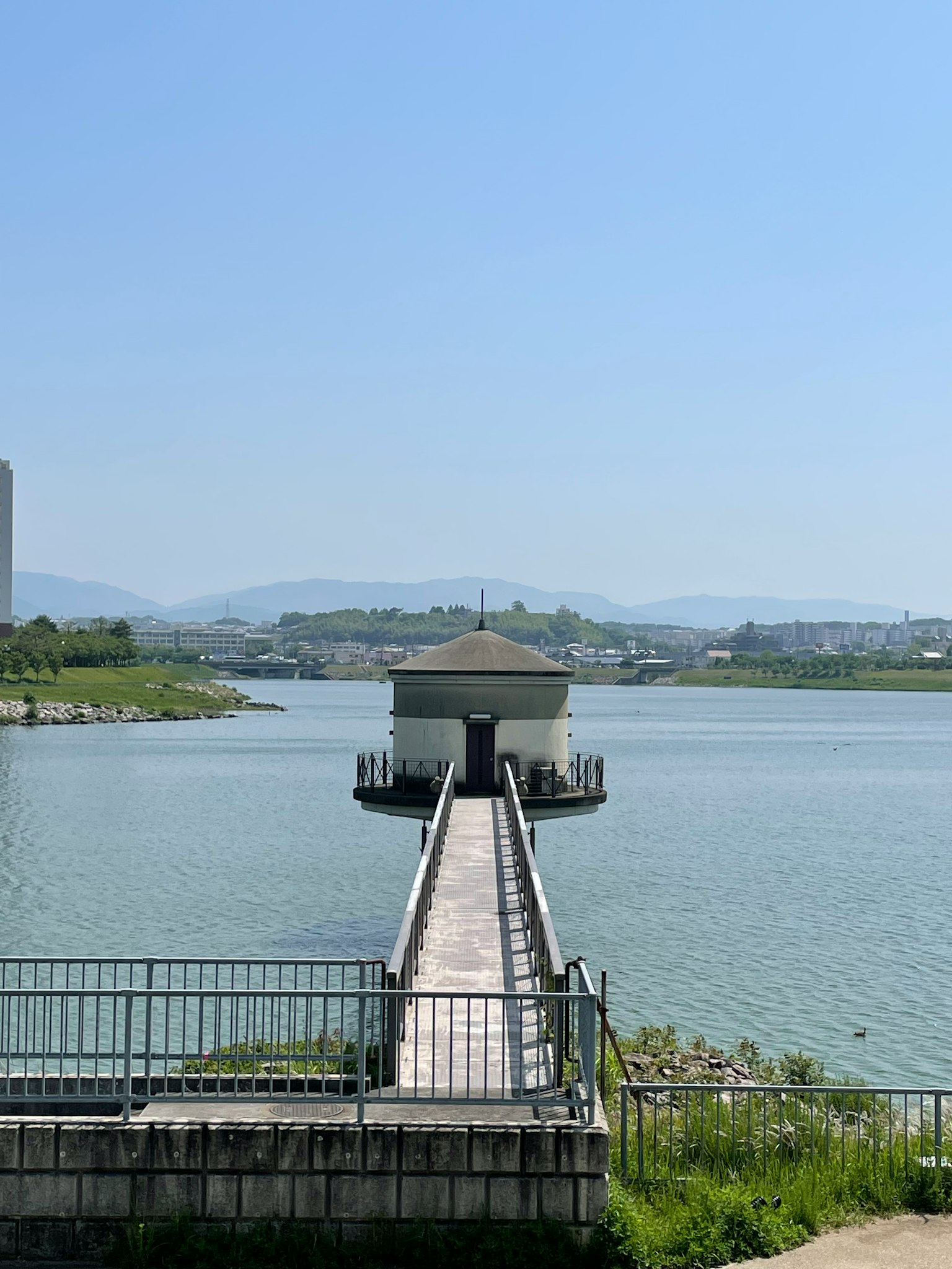 Un piccolo edificio sull'acqua con un lungo pontile sotto un cielo blu limpido