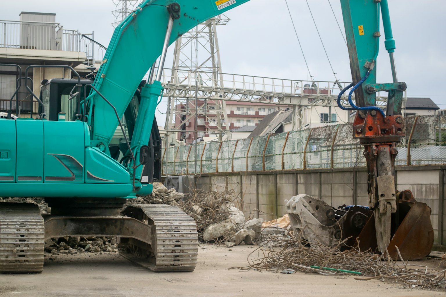 Cantiere di costruzione con escavatore blu e detriti di cemento circostanti