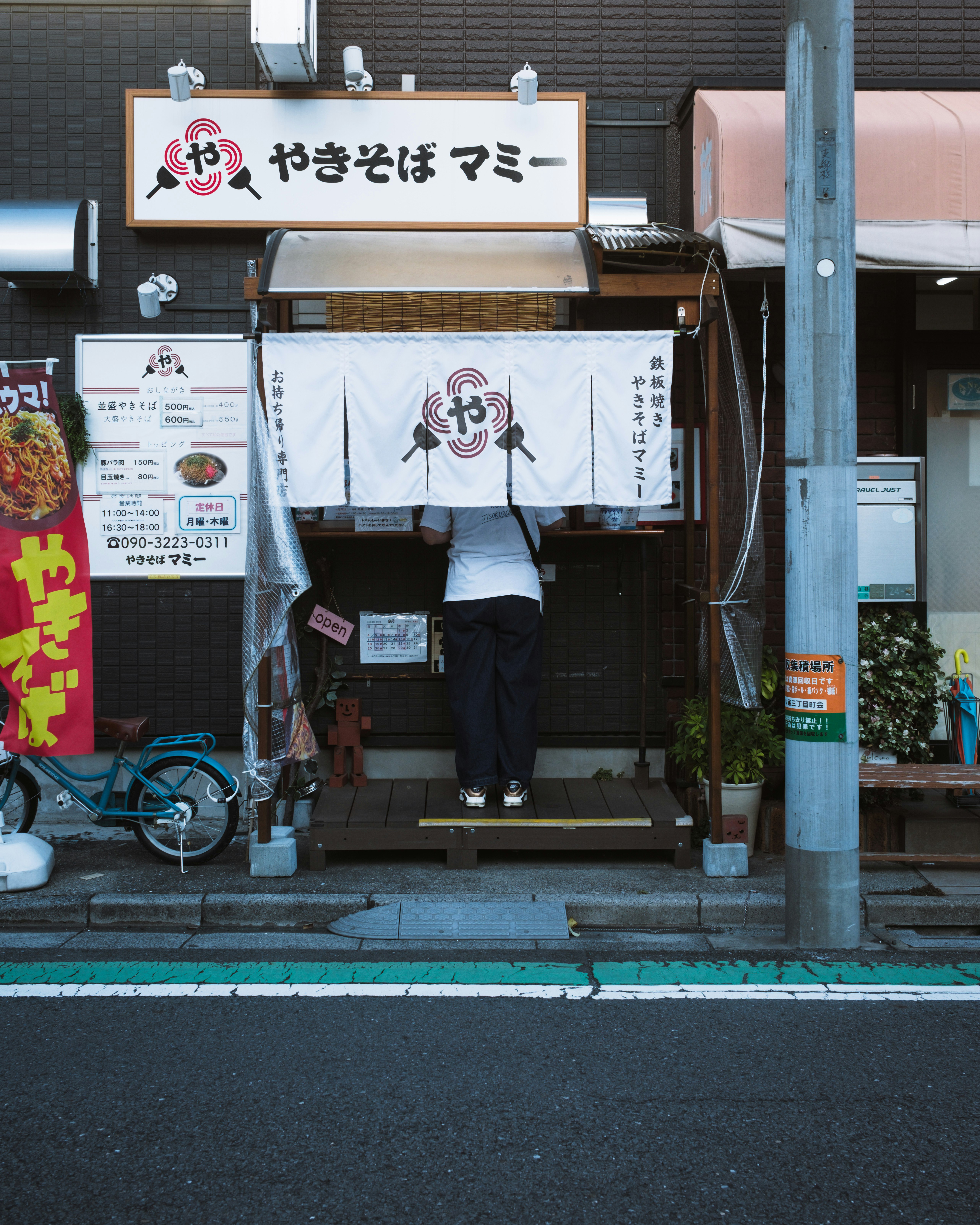 路地の屋台で焼きそばマシンと幟が並ぶ商店街の軒先