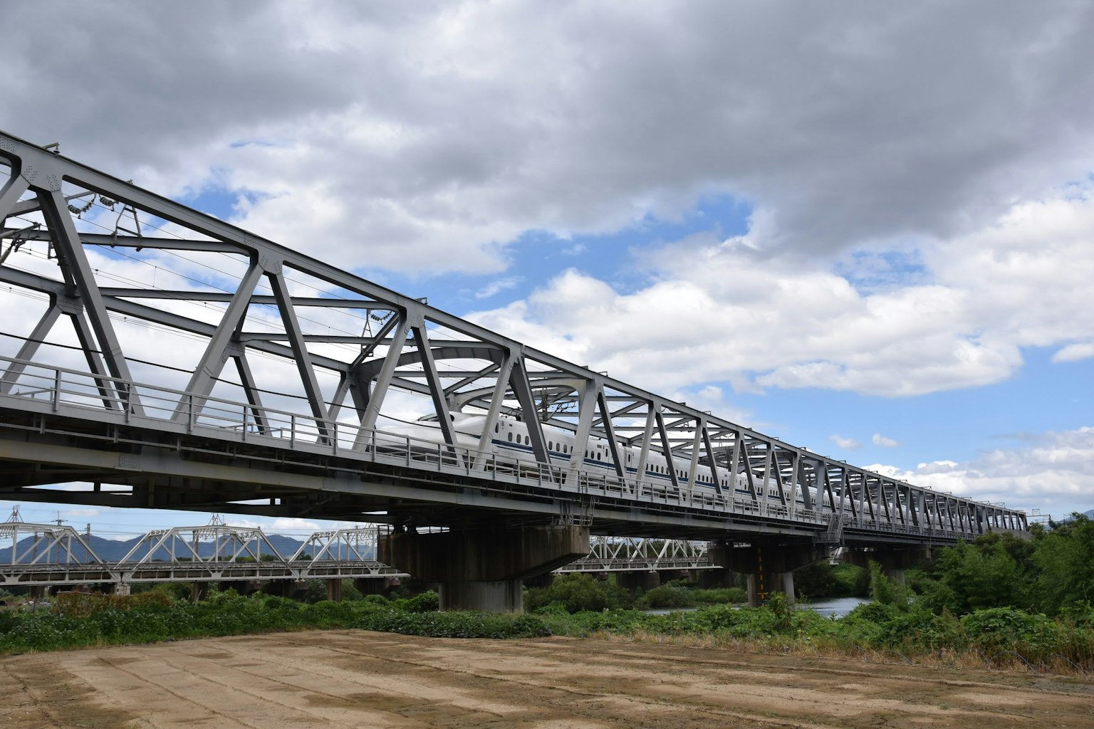Ponte in acciaio a traliccio argentato che si estende sotto un cielo nuvoloso