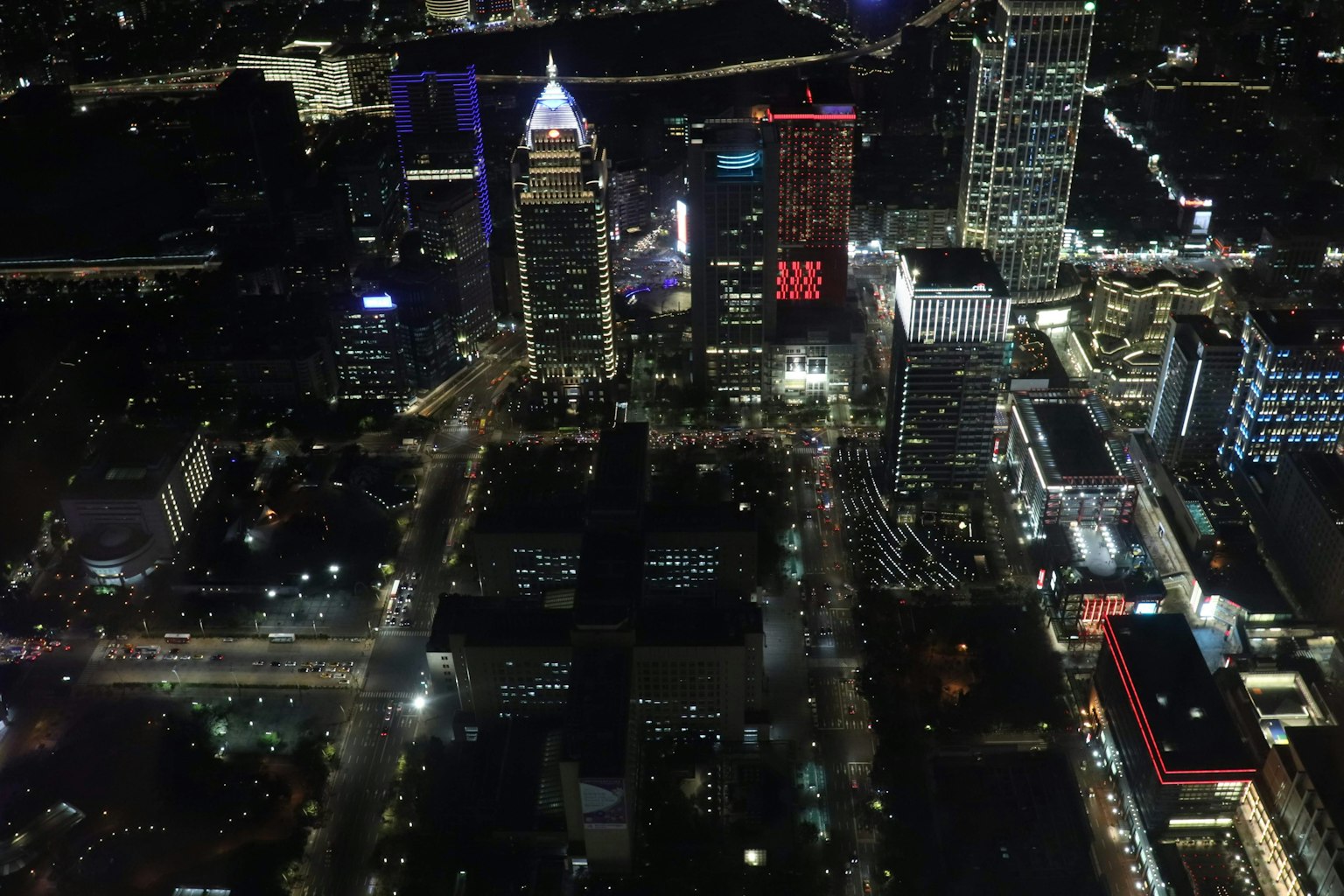 Vista aérea de una ciudad de noche con rascacielos modernos y luces de neón brillantes