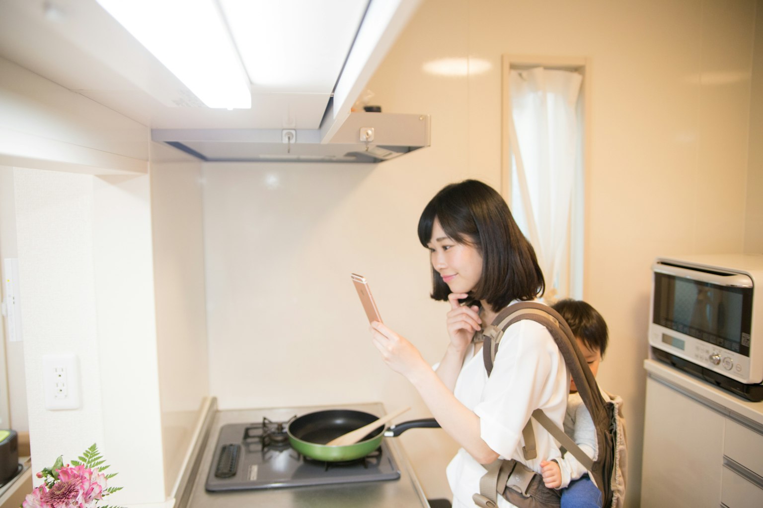 Mujer mirando su smartphone mientras cocina en la cocina