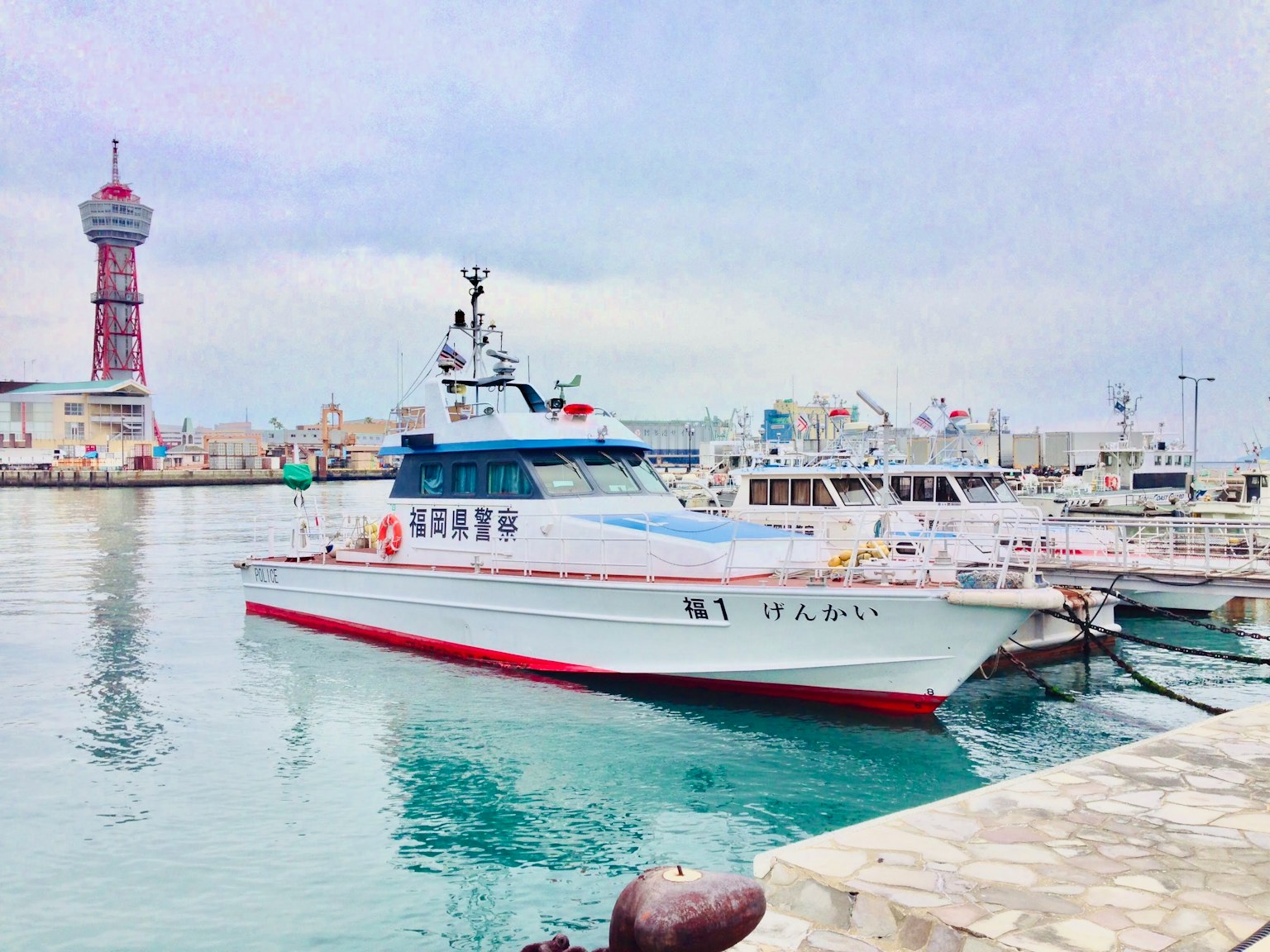 Ein weißes und rotes Boot im Hafen mit einem Turm im Hintergrund