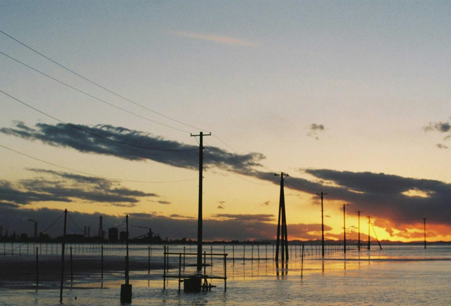 Landscape featuring power poles silhouetted against a sunset sky