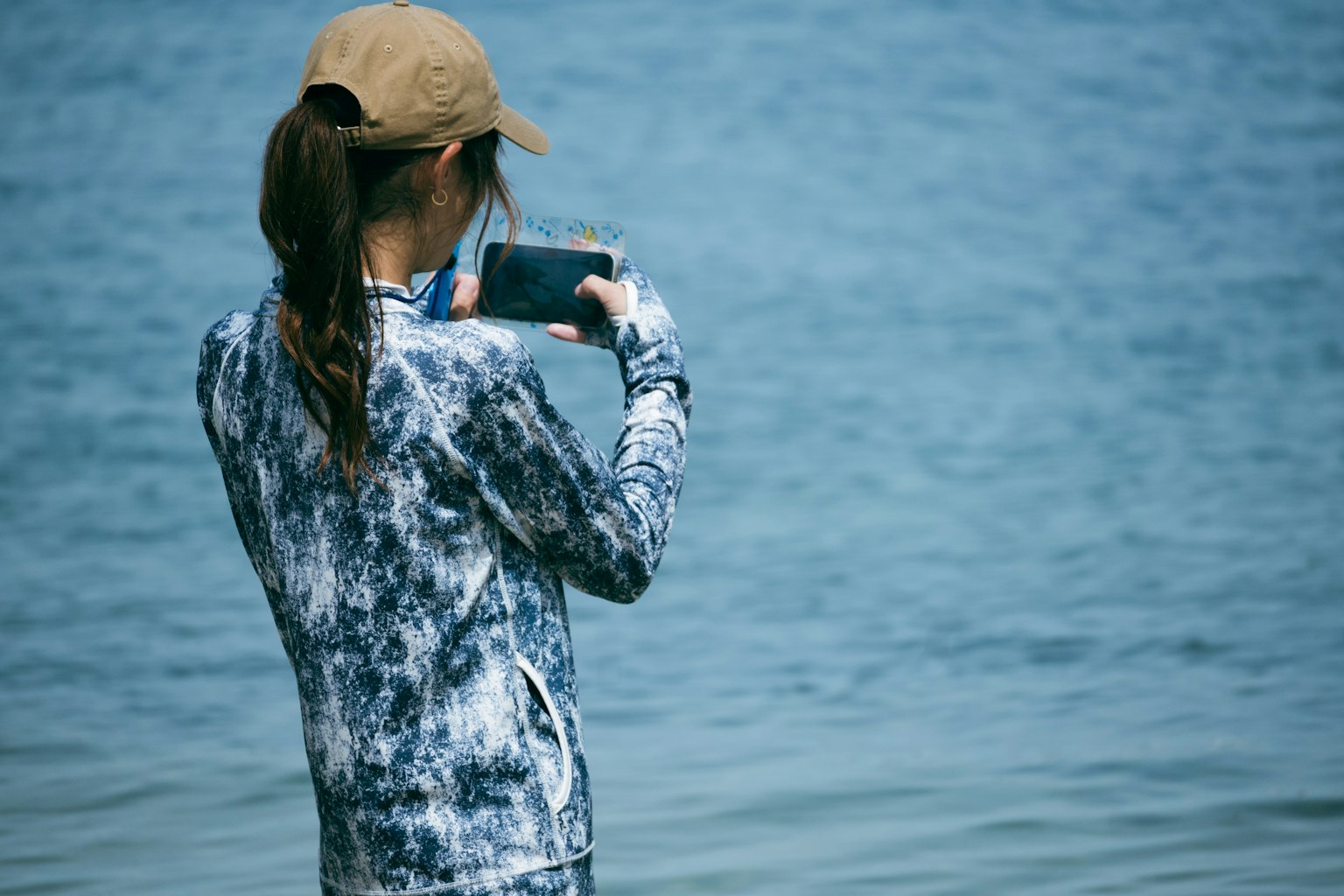 Woman holding smartphone by the sea
