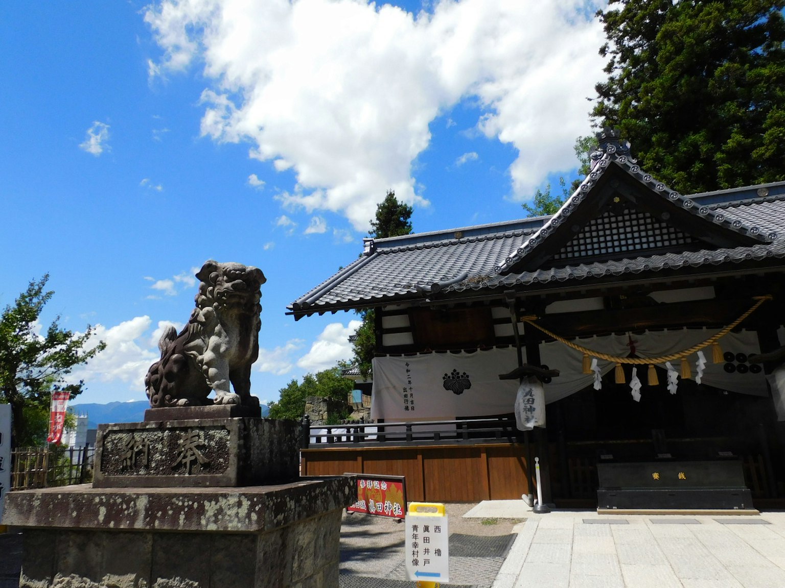 Exterior of a shrine with a guardian lion statue under a blue sky