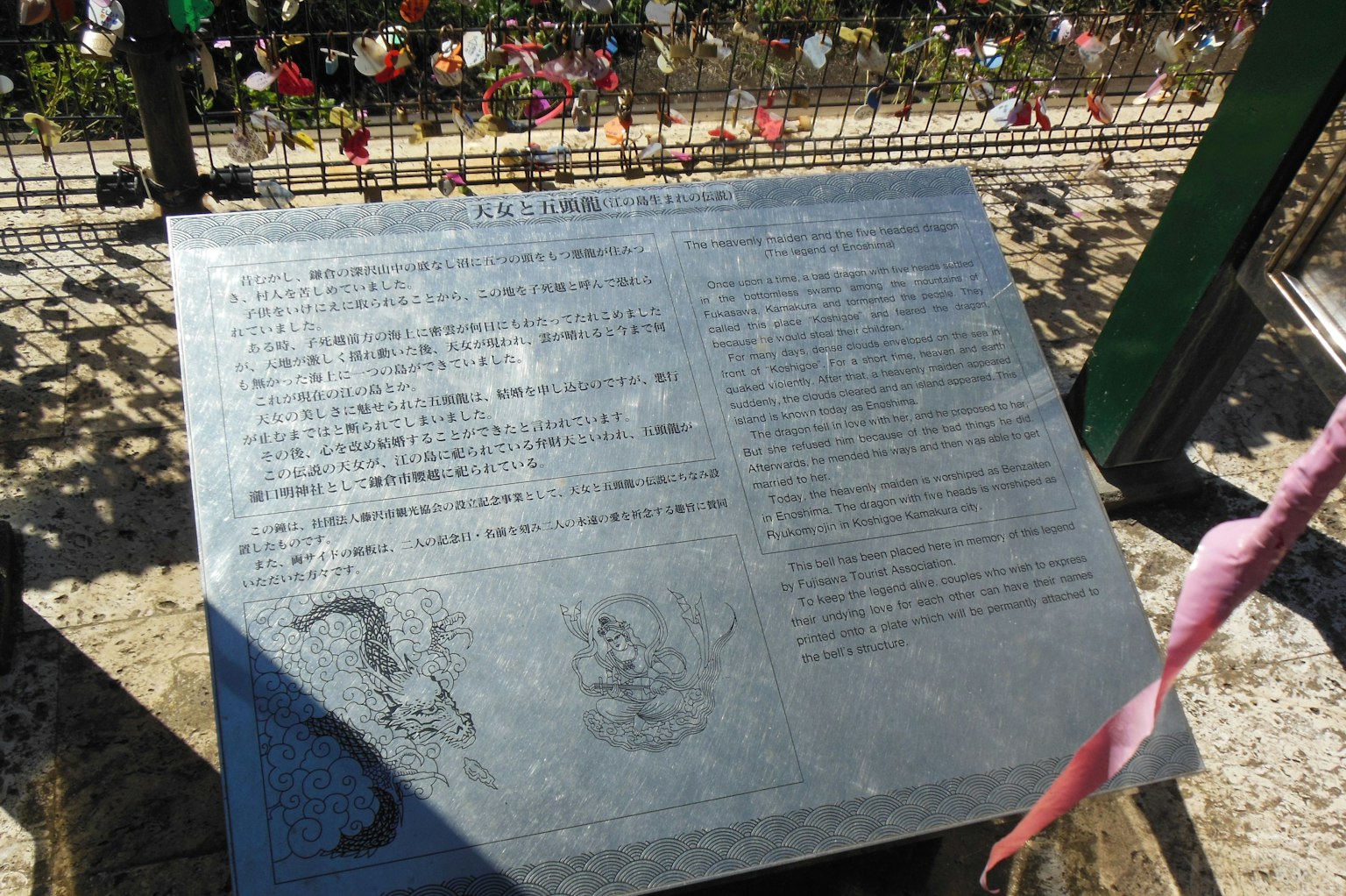 Bronzetafel mit eingraviertem Text umgeben von Blumen im Hintergrund