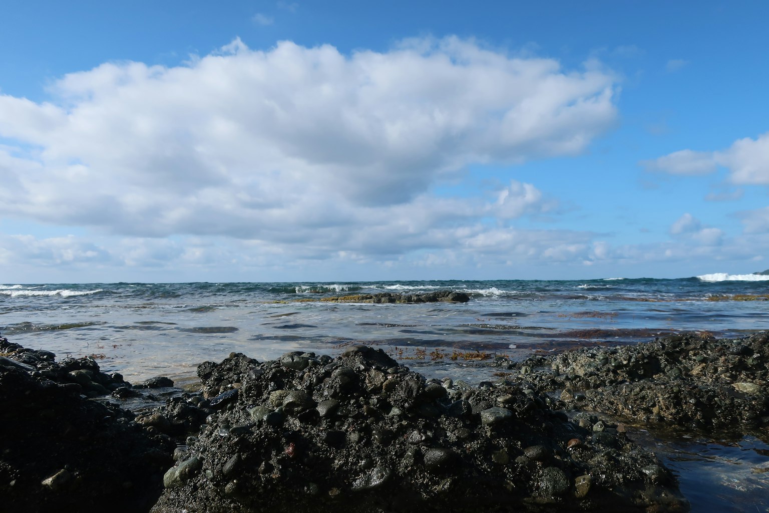 Vue panoramique de l'océan bleu et des nuages avec un premier plan rocheux