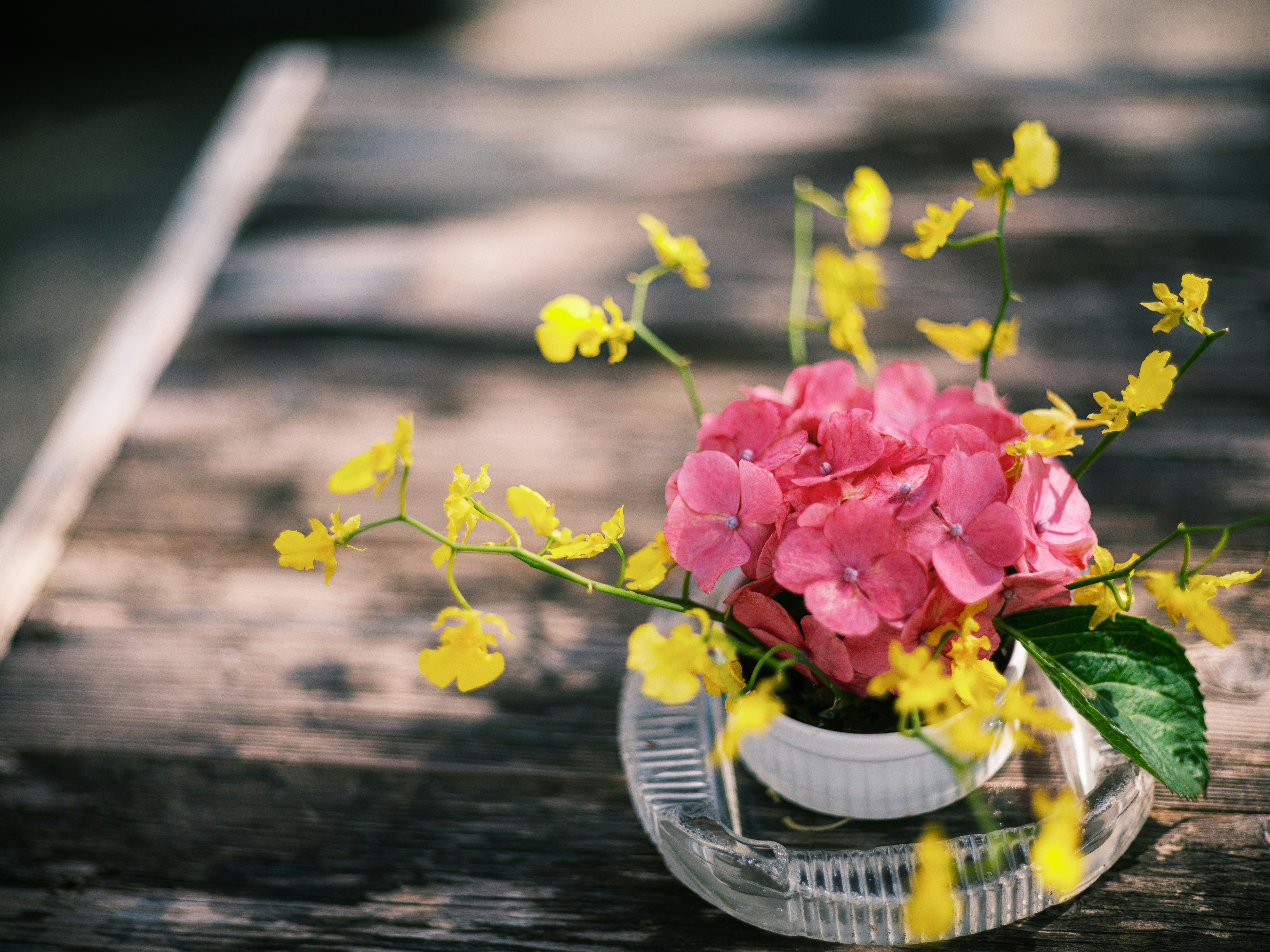 木製の板の上に置かれたピンクの花束と黄色い花