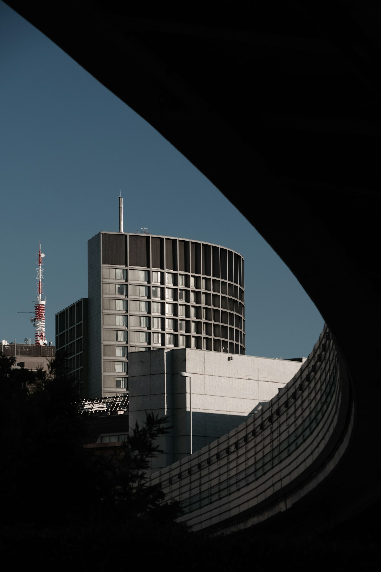 Modern building with curved foreground and tall antenna