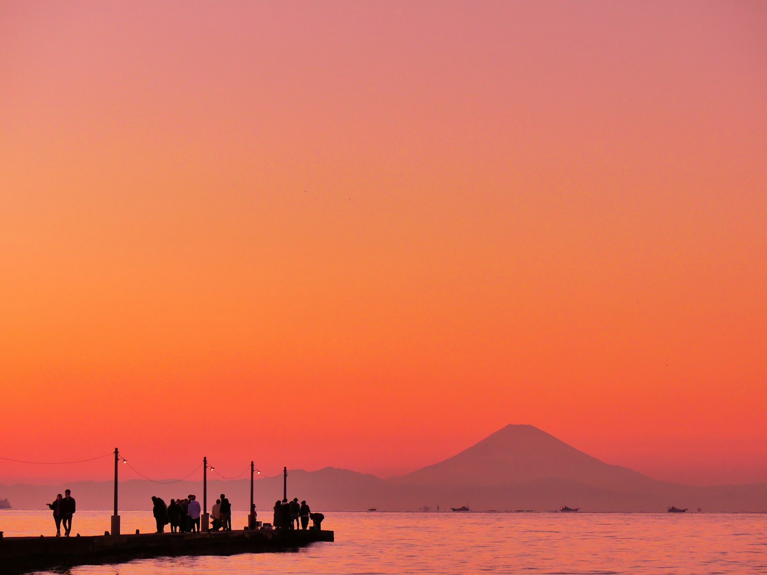 Bellissimo tramonto sul mare con il Monte Fuji sullo sfondo e silhouette di persone