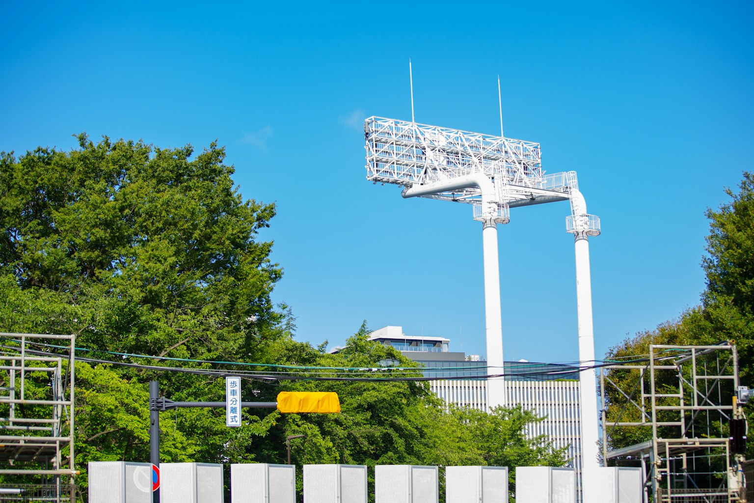 Large floodlights under a clear blue sky with surrounding trees