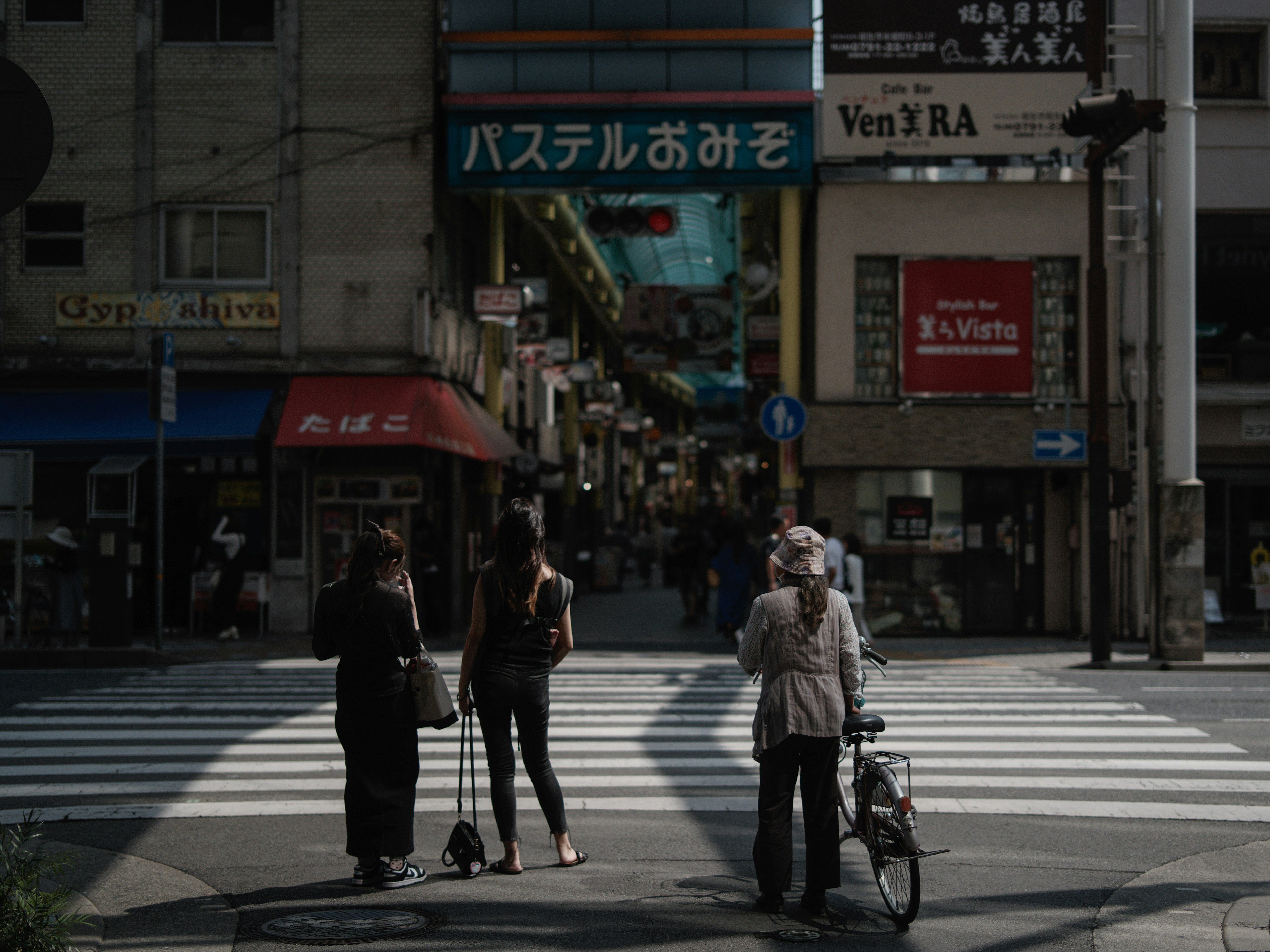路地の横断歩道を歩く人と自転車のある商店街の街並み