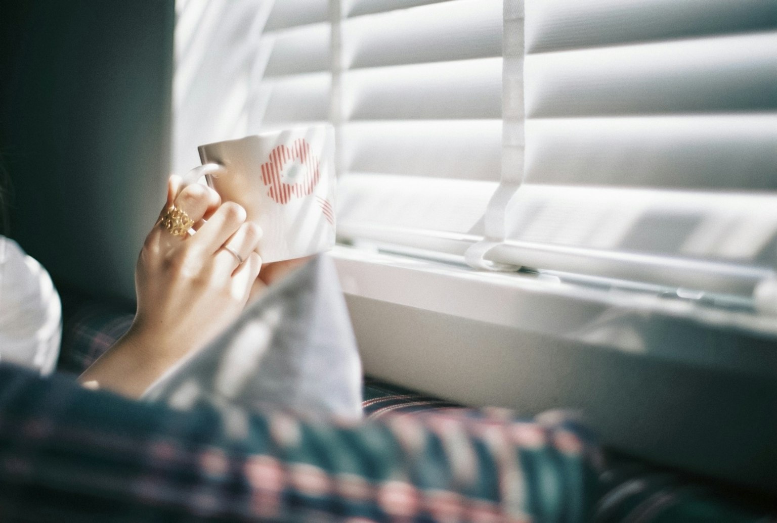 Close-up of hands holding a coffee cup by the window