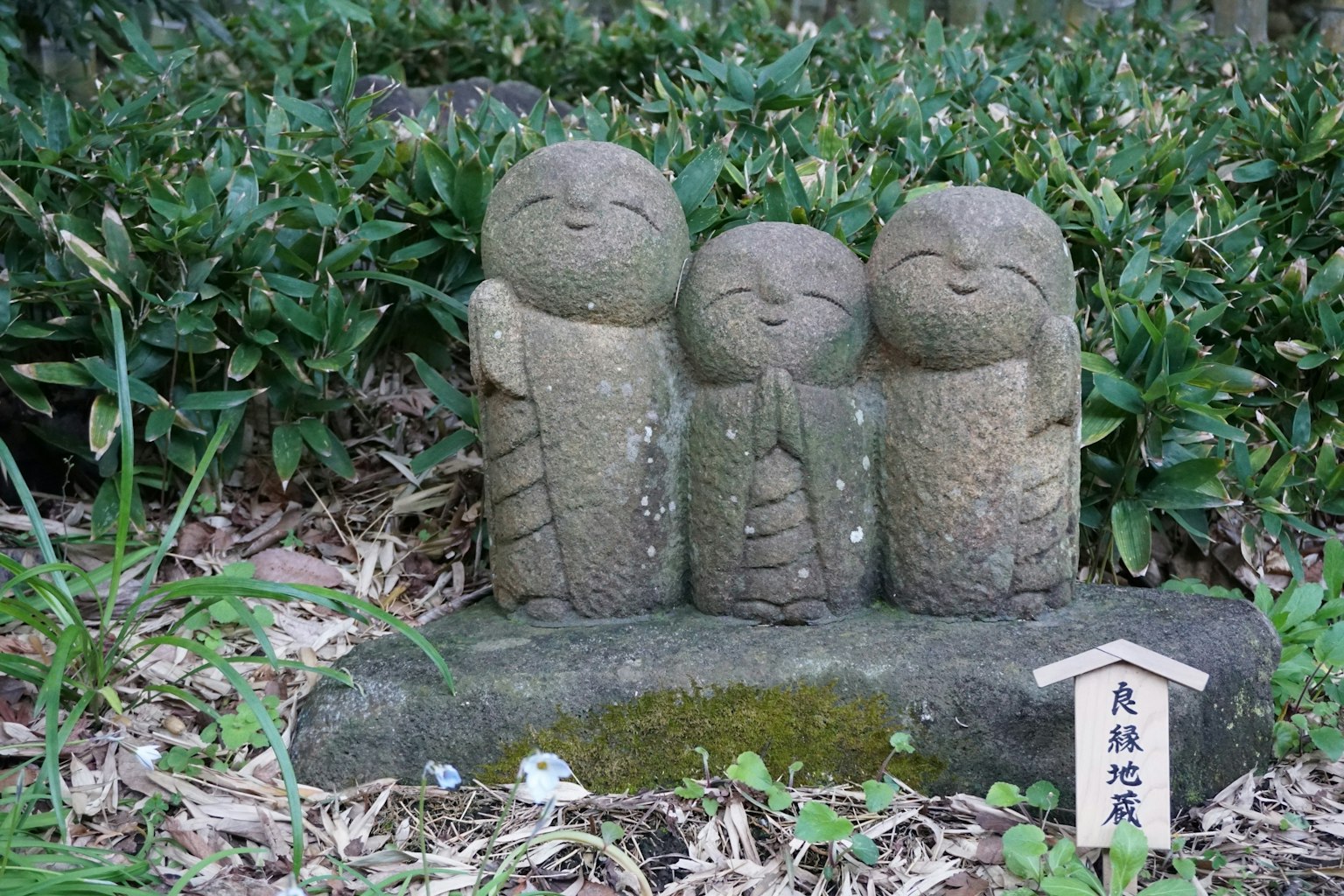 Tres figuras de piedra en un entorno verde