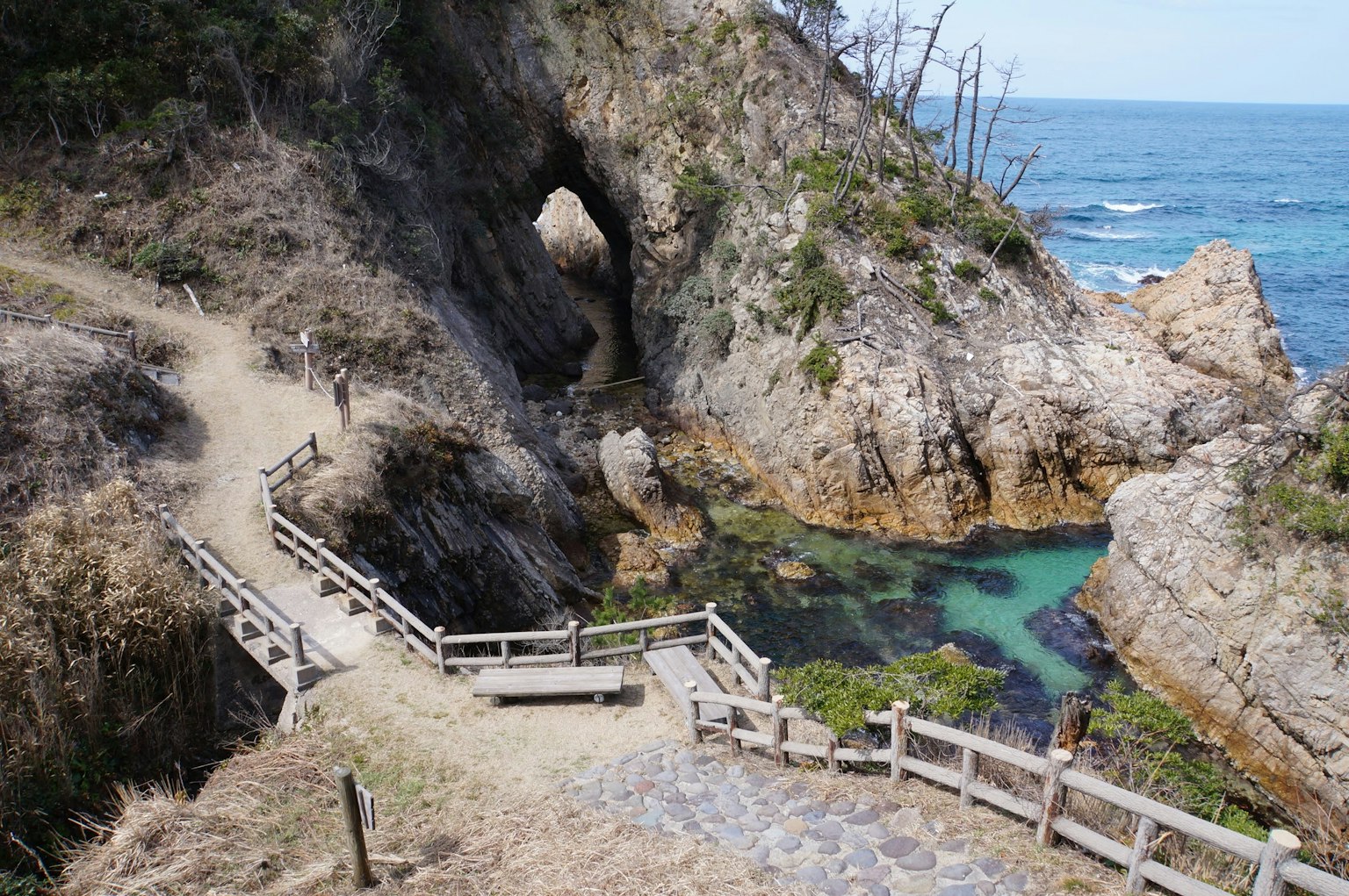 Coastal rocky landscape with a path turquoise water pools and wooden bridge