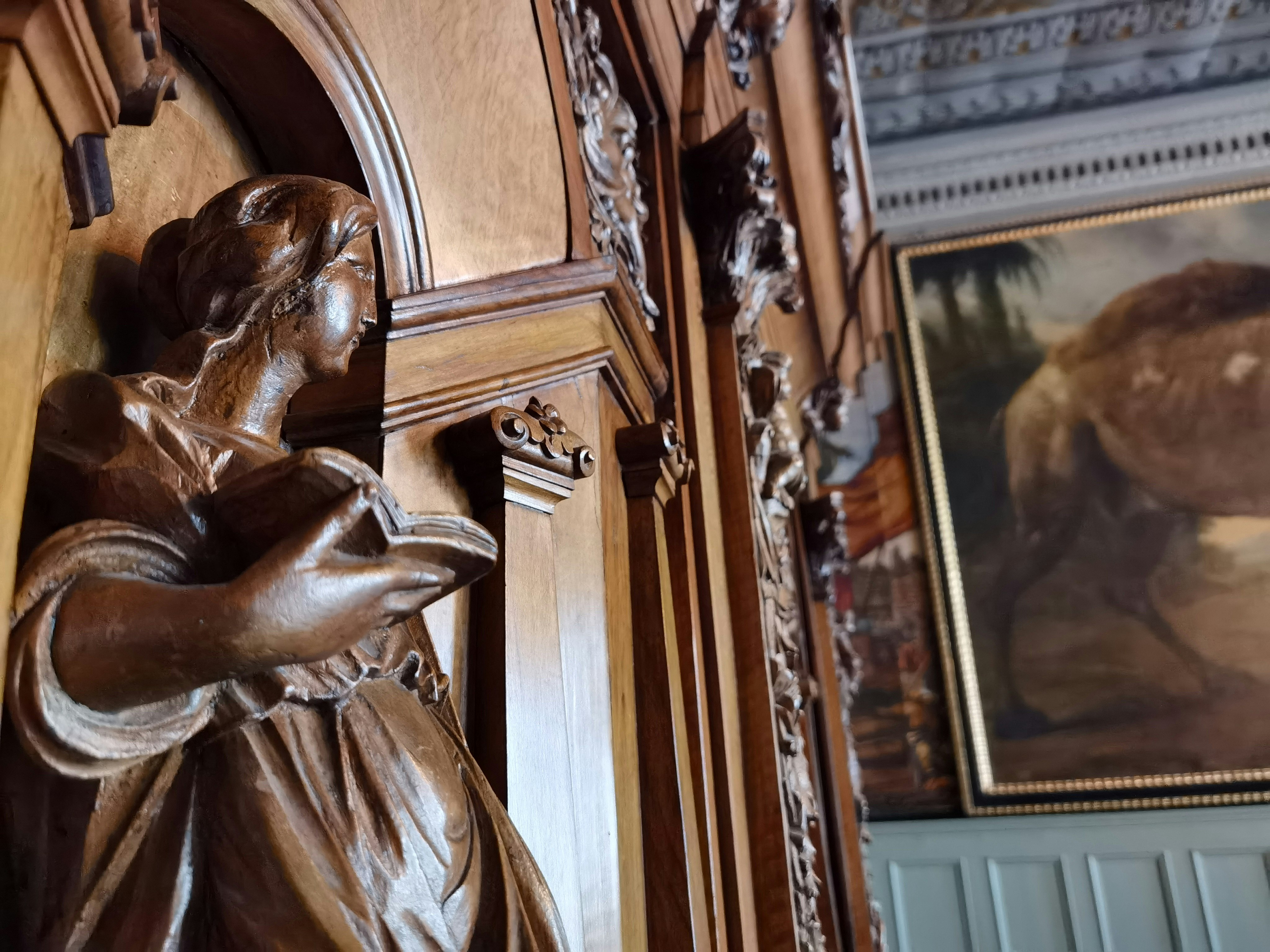 Indoor wall with framed artwork and a bronze sculpture figure