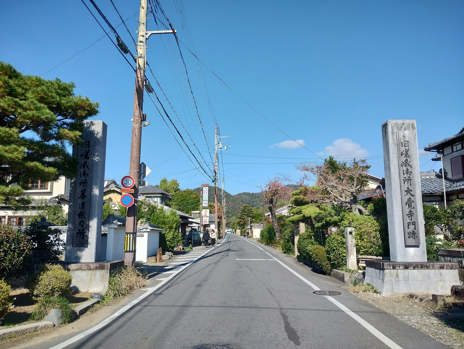 Quiet Japanese street featuring stone gates and blue sky