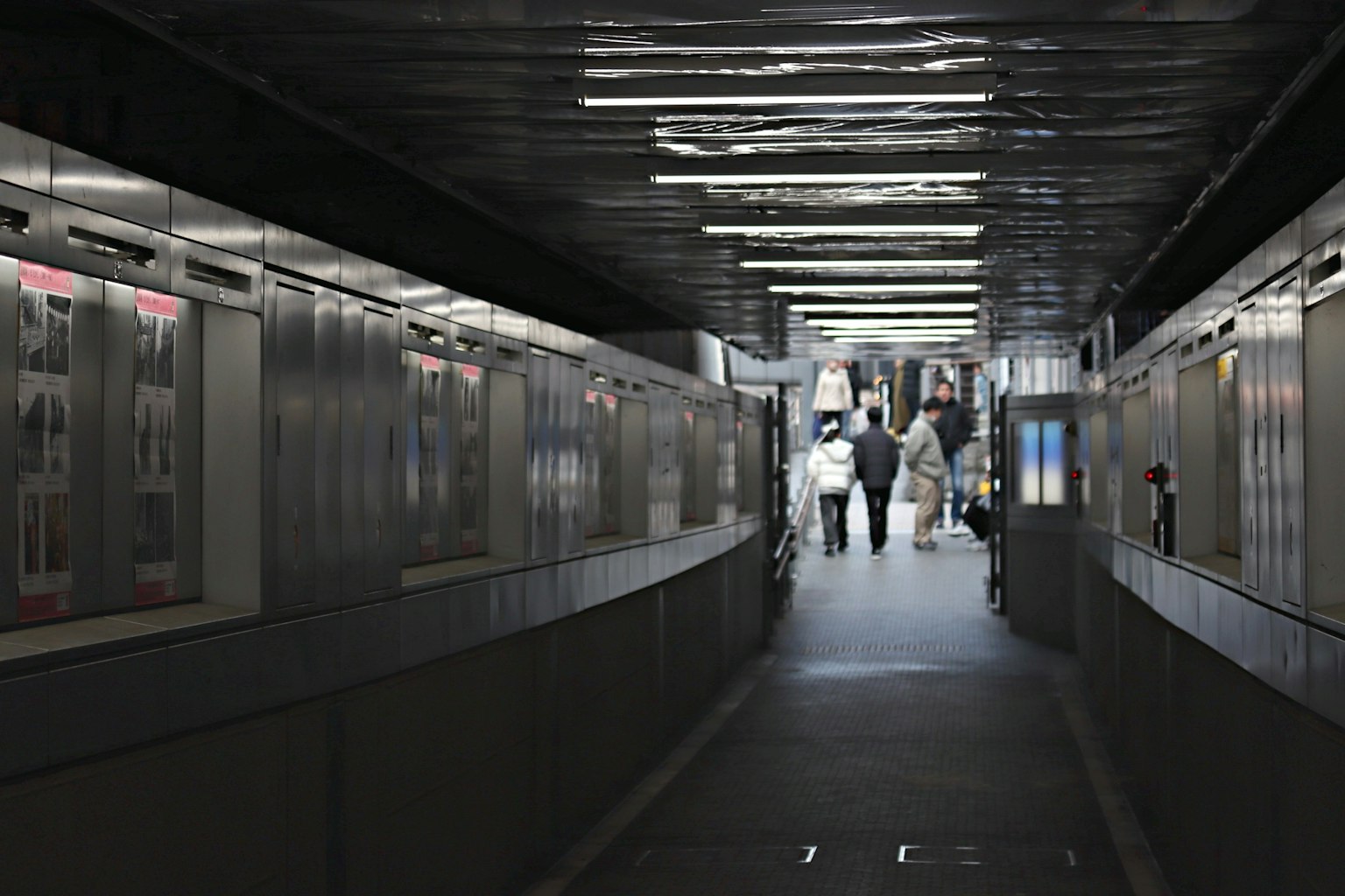 Corridoio poco illuminato con persone che camminano