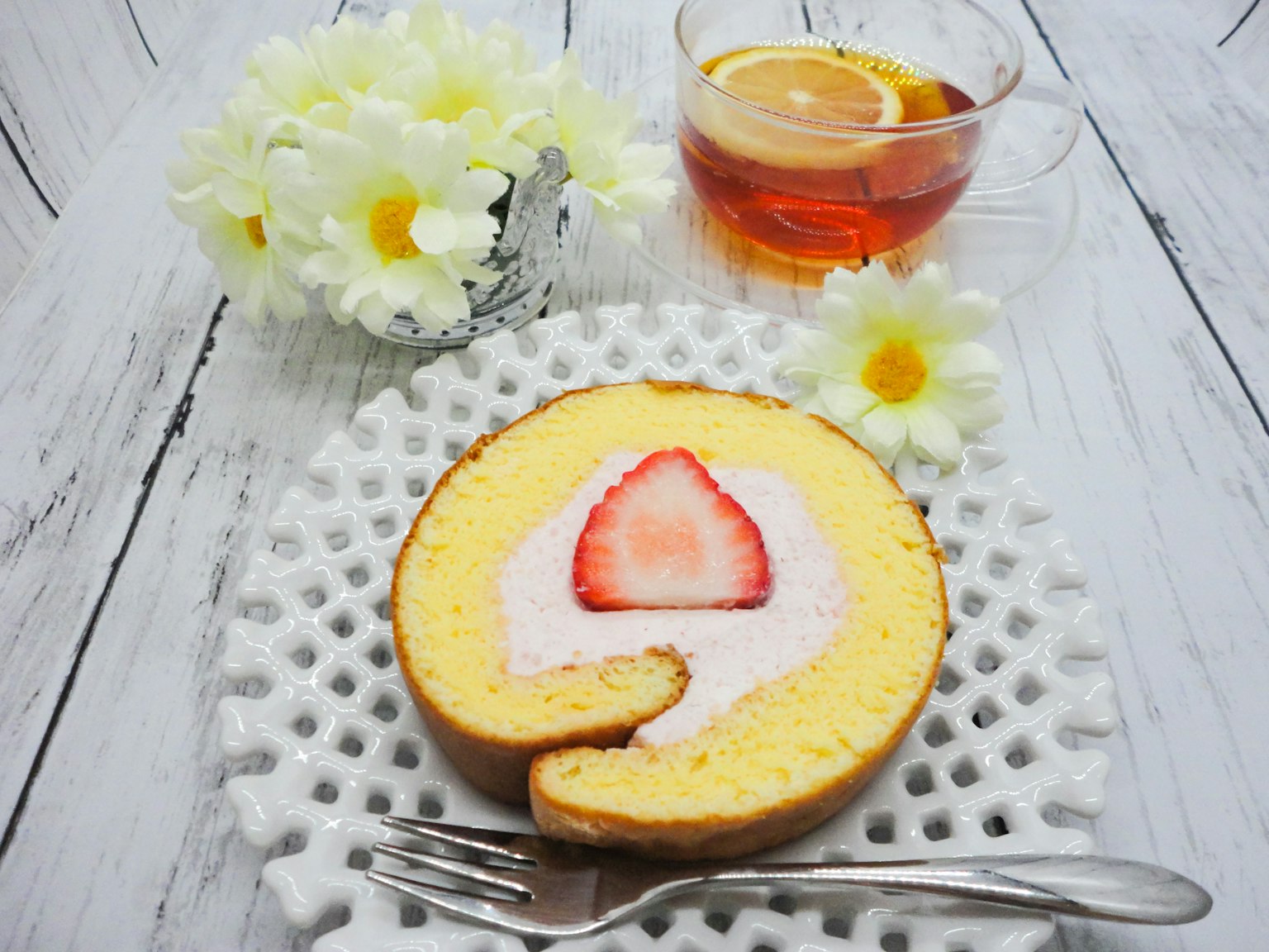 Pastel enrollado de fresa en un plato decorativo con flores y té