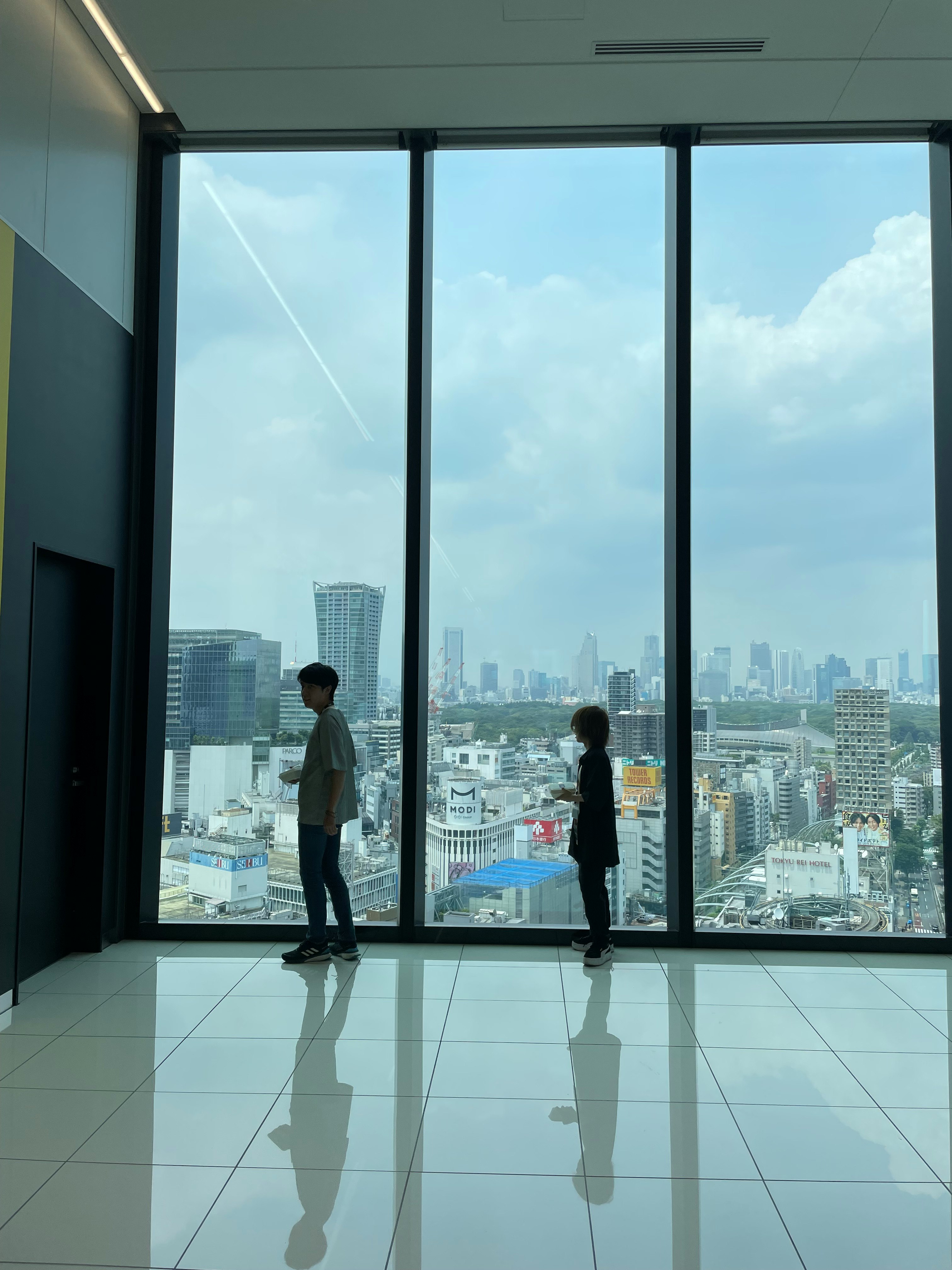 people standing inside a modern room with a panoramic city view through large windows