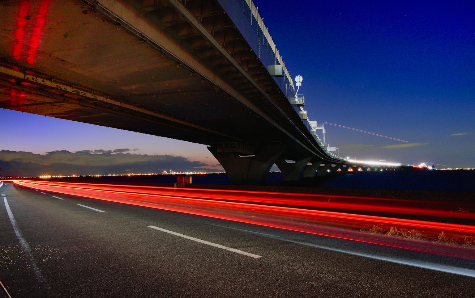 Un puente bajo el cielo nocturno con luces de coches en movimiento