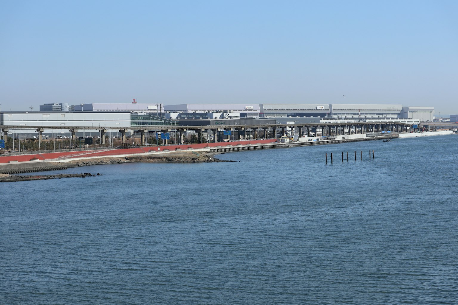 Installation industrielle au bord de l'eau avec un ciel bleu clair