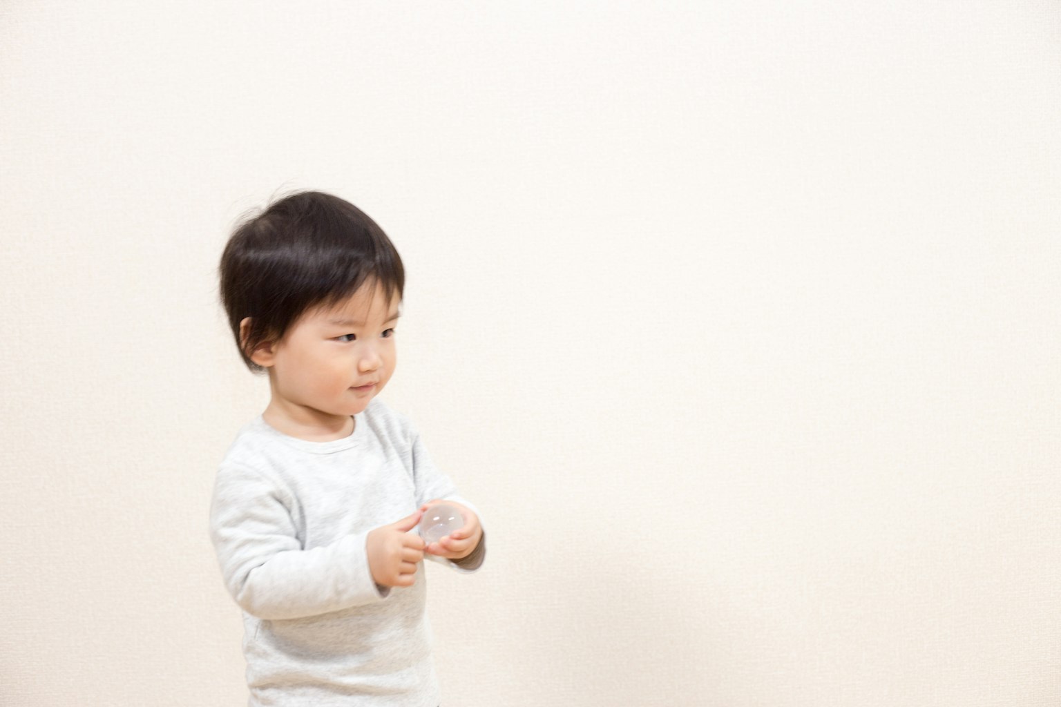 Un enfant tenant un petit objet devant un fond blanc