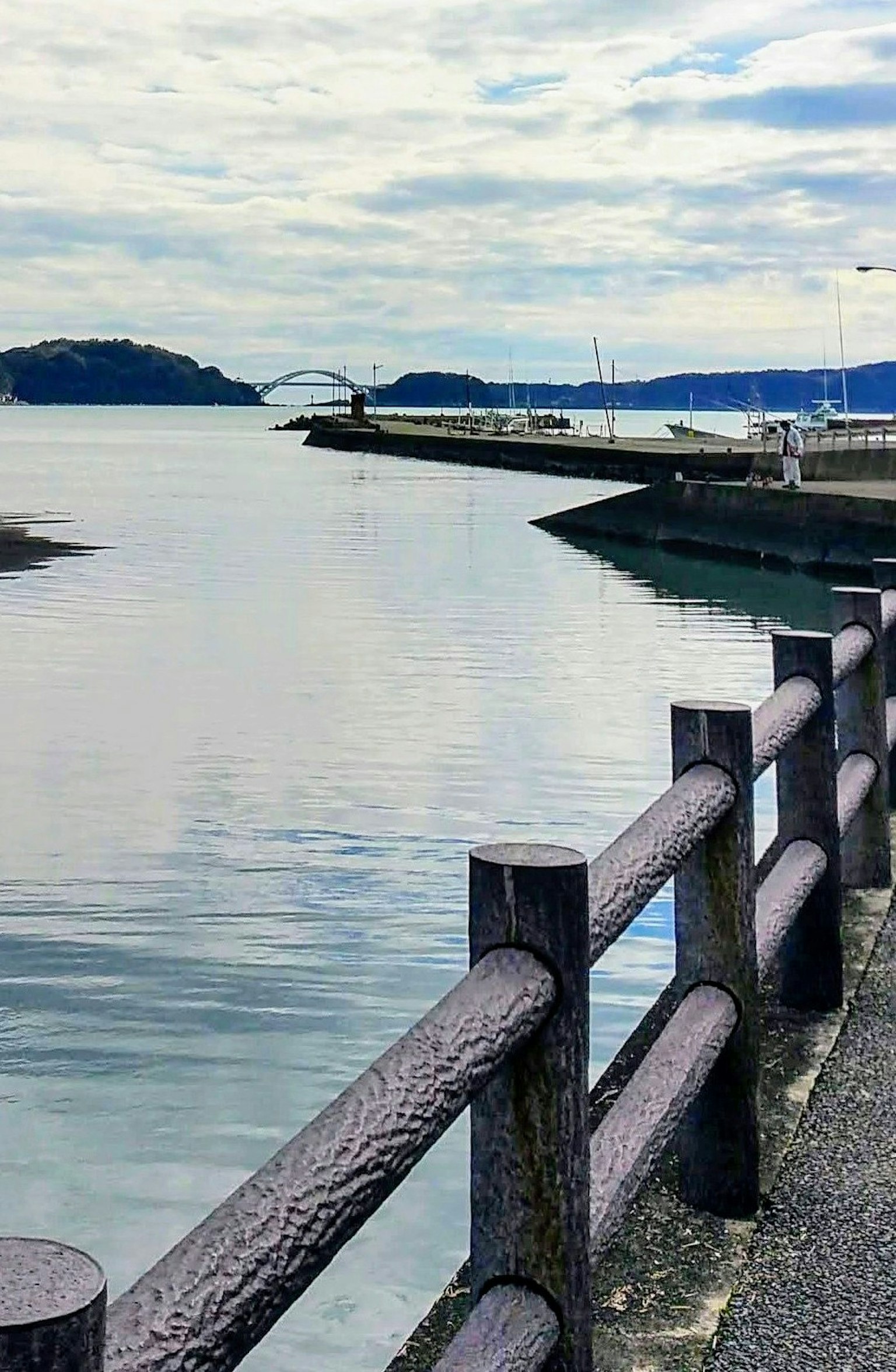 Serene view of the sea with a pier reflected under a cloudy sky