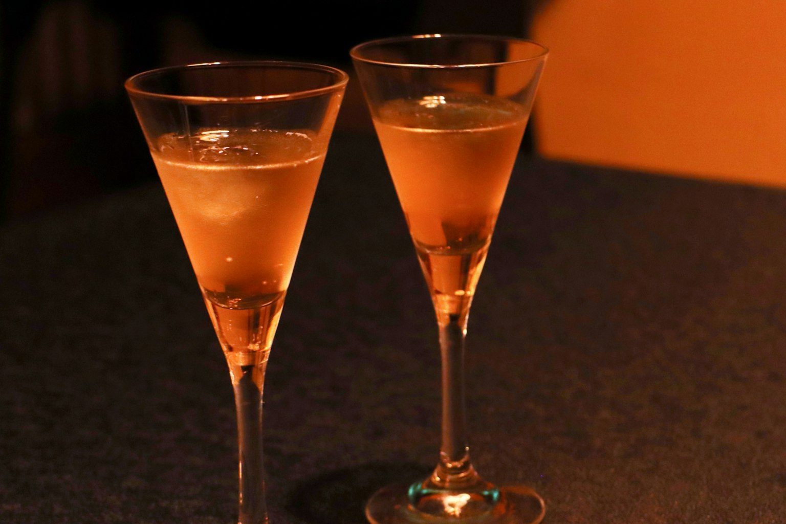 Due bicchieri di champagne pieni di una bevanda dorata brillano su uno sfondo scuro