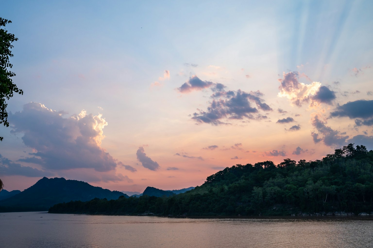 Pemandangan sungai tenang dengan langit matahari terbenam dan pegunungan