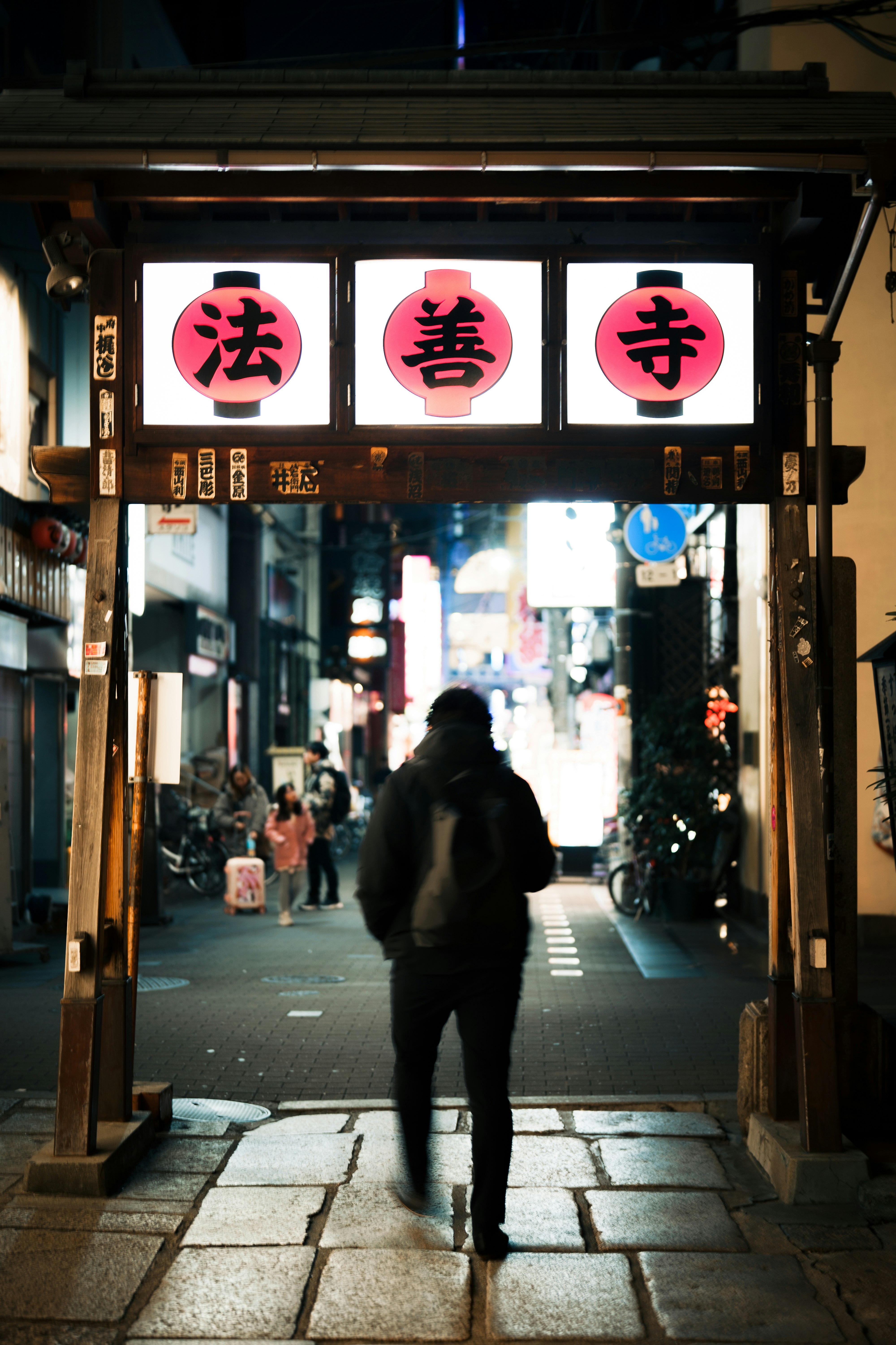 ruelle de nuit avec des lanternes portant « 法 », « 善 » et « 寺 »