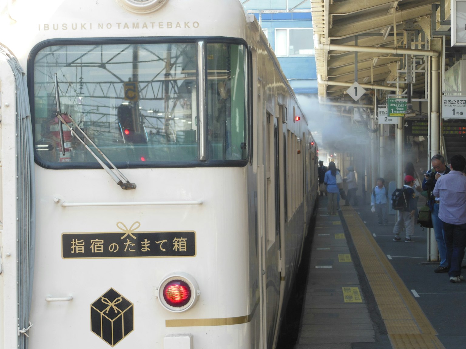 Treno bianco fermo in stazione con passeggeri sulla banchina