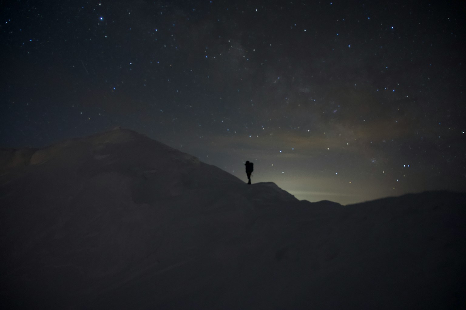 在星空下站著的人影與被雪覆蓋的山
