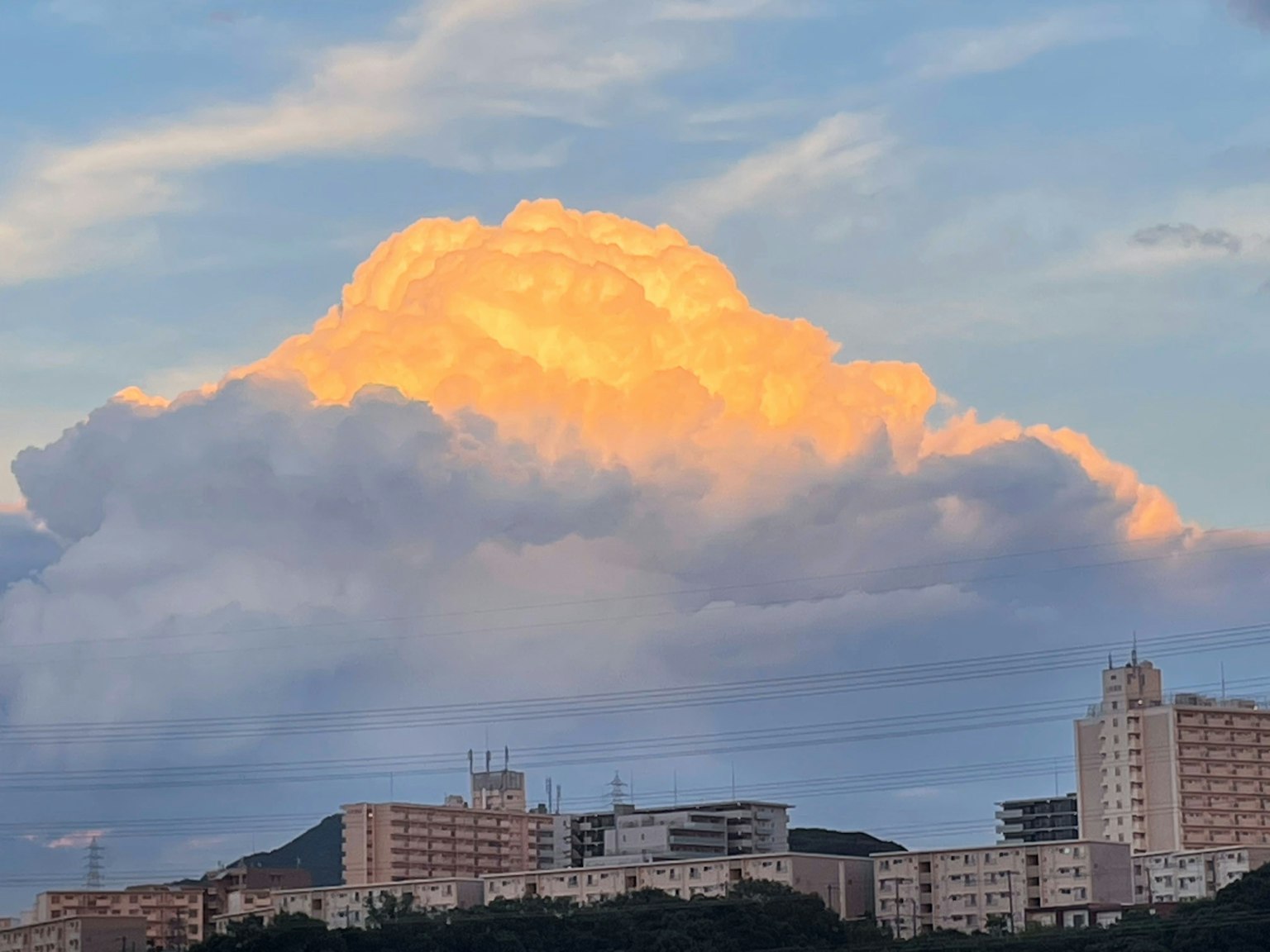 Wolken, die vom Sonnenuntergang über einer Stadtlandschaft beleuchtet werden