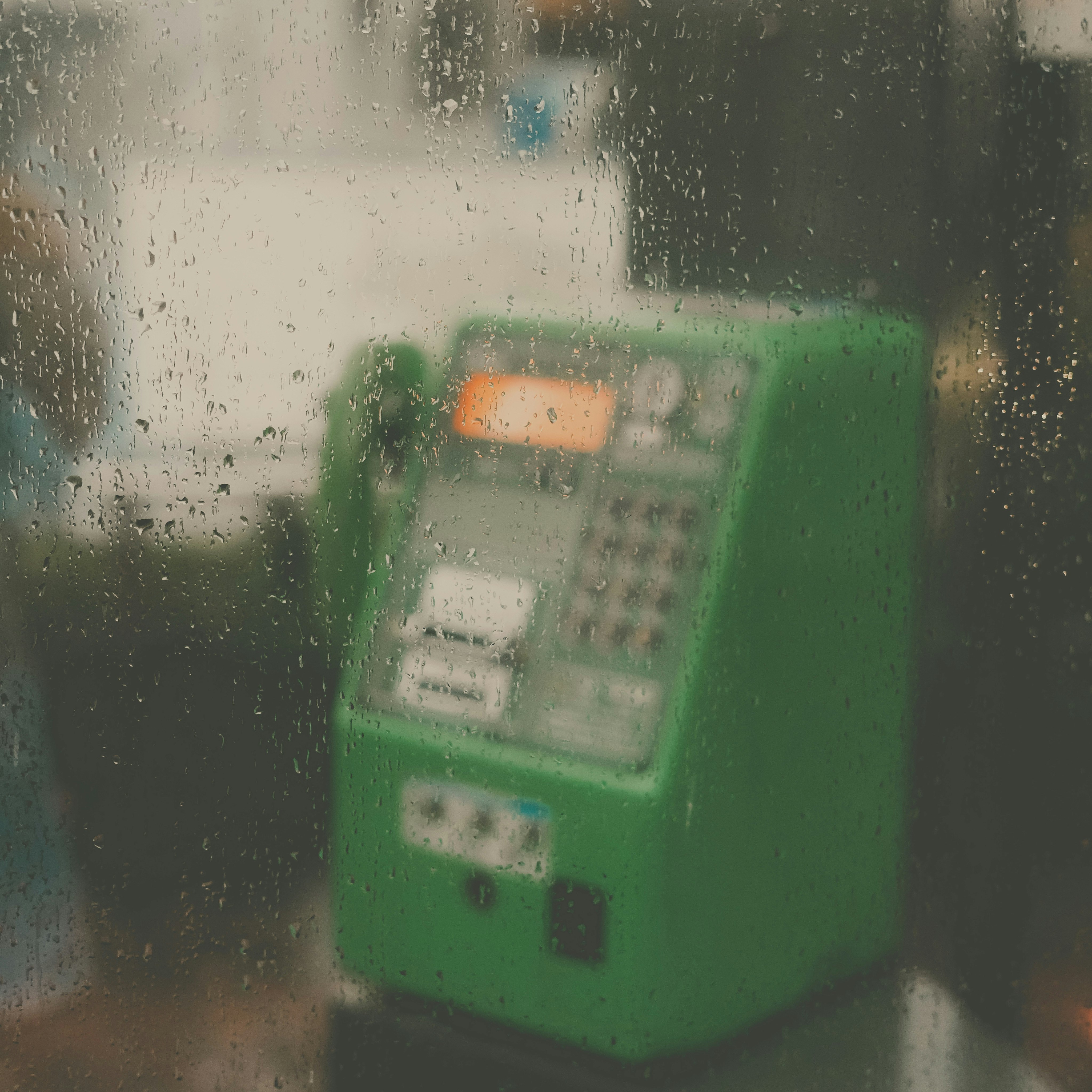 雨滴沾满的窗户后方的绿色自动售货机