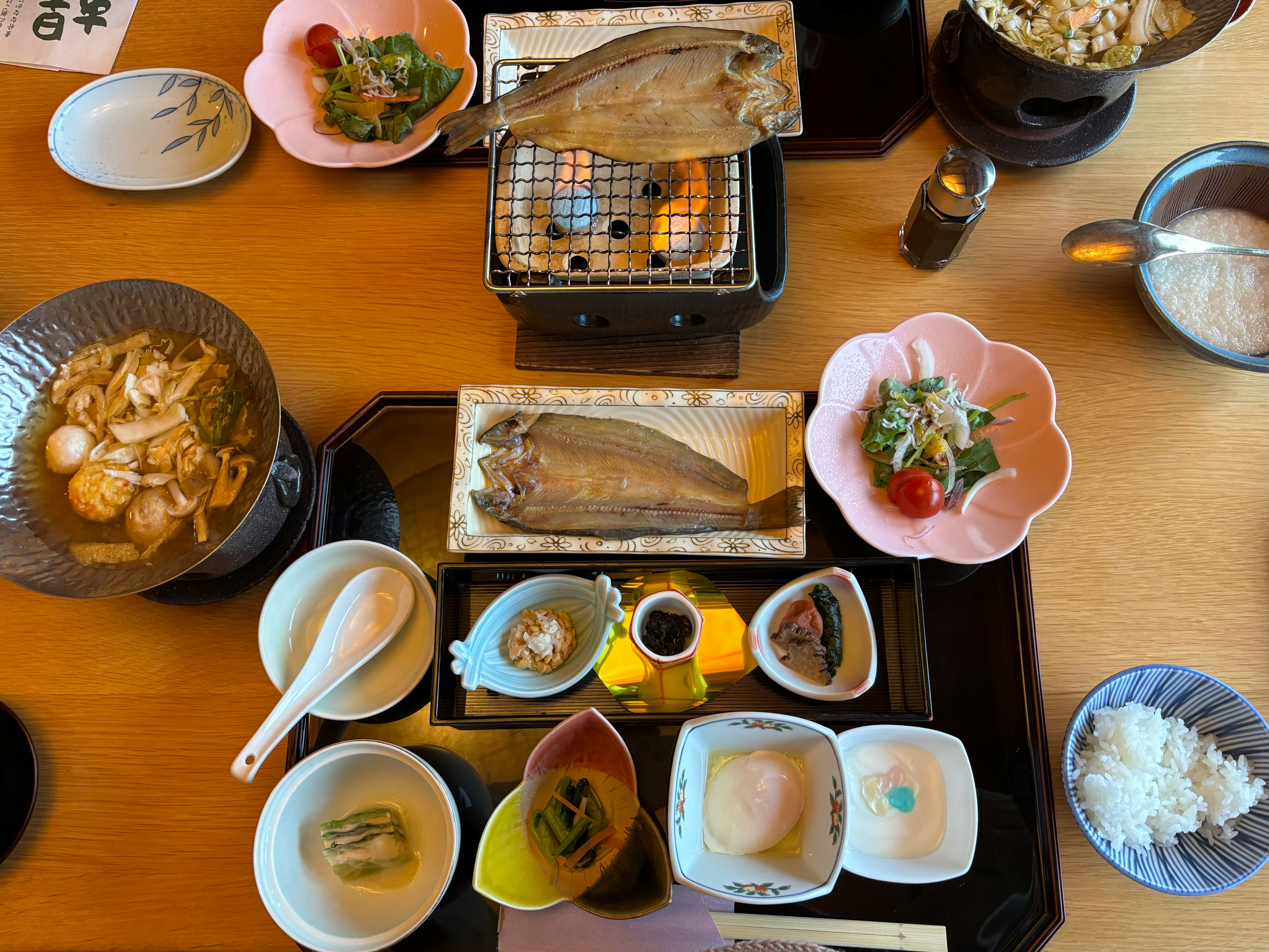 卓上に並ぶ和食の定食と小鉢、湯気のある食卓