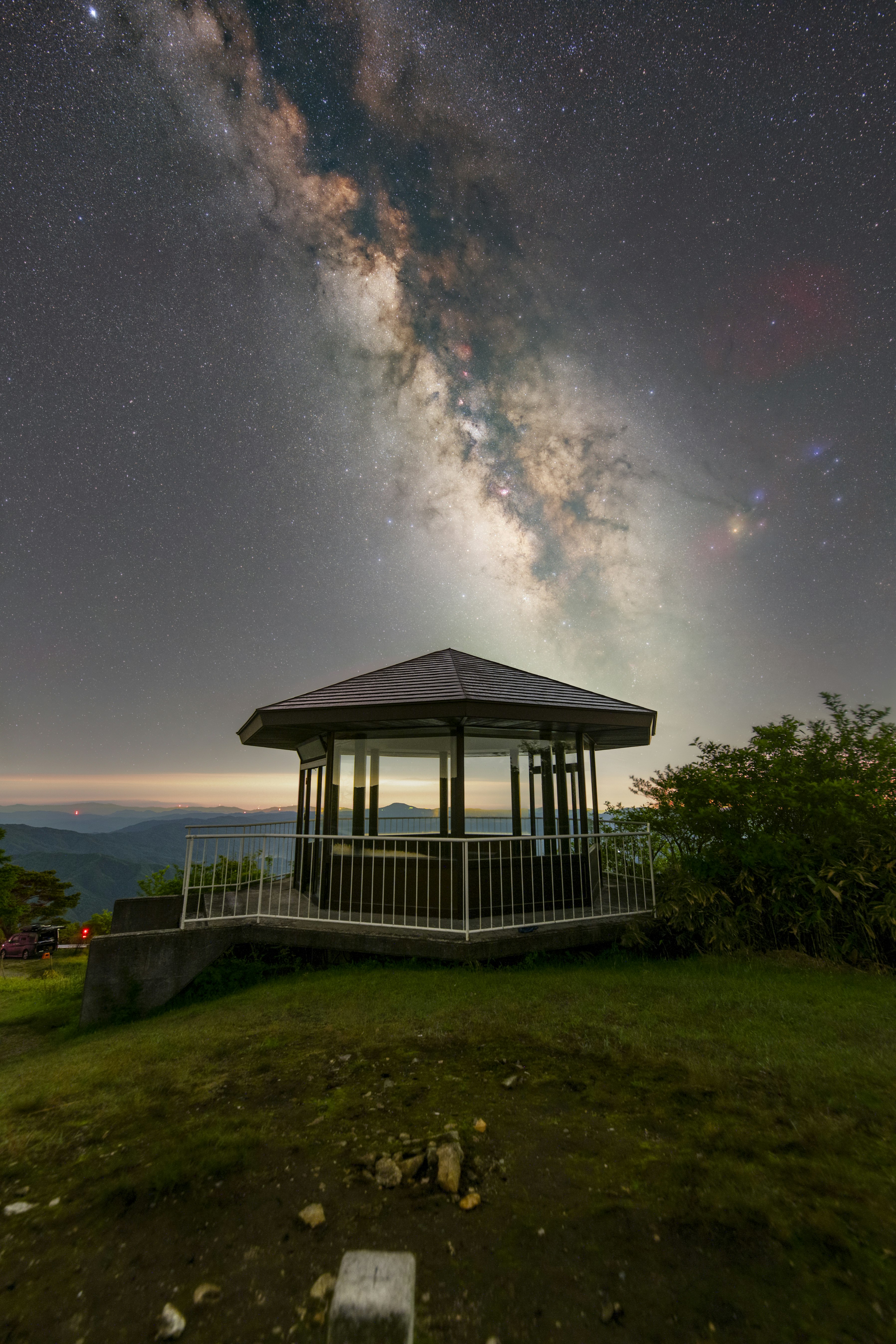 a grassy viewpoint pavilion under the Milky Way night sky