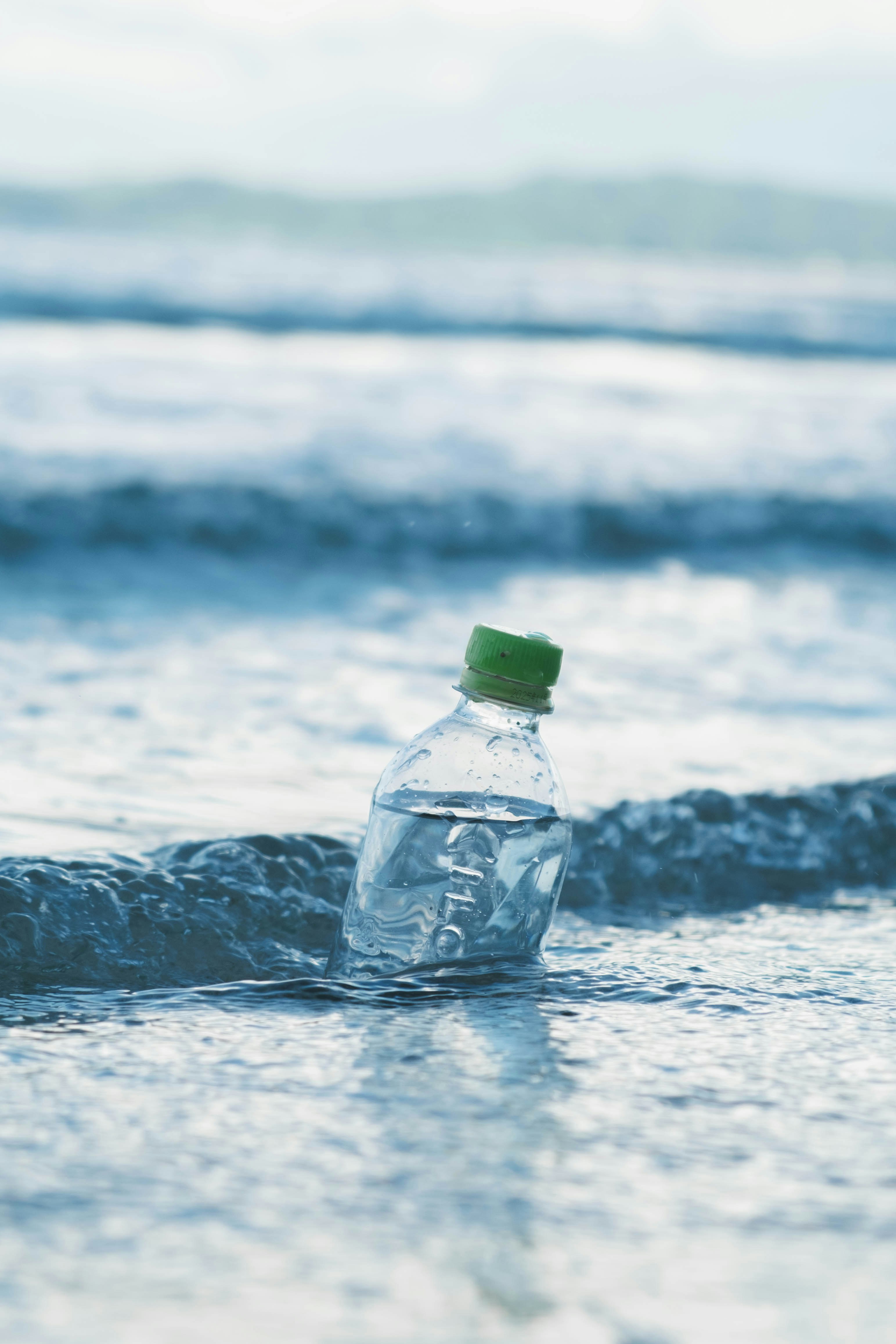 plastic bottle with green cap in ocean waves