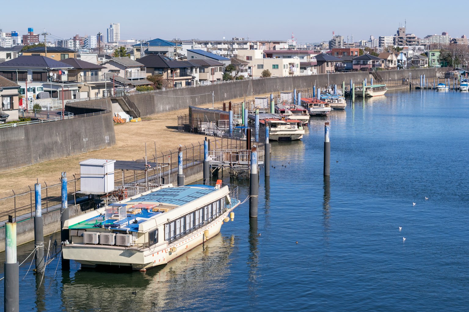 Botes amarrados junto a un río con edificios residenciales al fondo