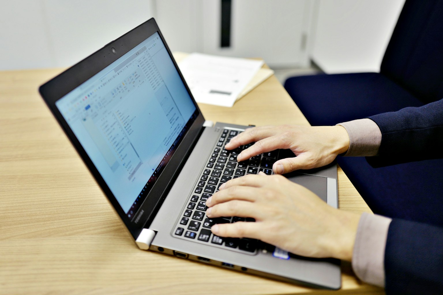 Nahaufnahme von Händen, die auf einer Laptop-Tastatur tippen