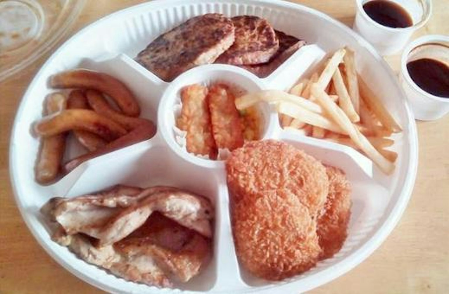 다양한 음식이 담긴 흰색 접시에는 프라이드 치킨 구운 고기 감자튀김과 튀긴 바나나가 포함되어 있다