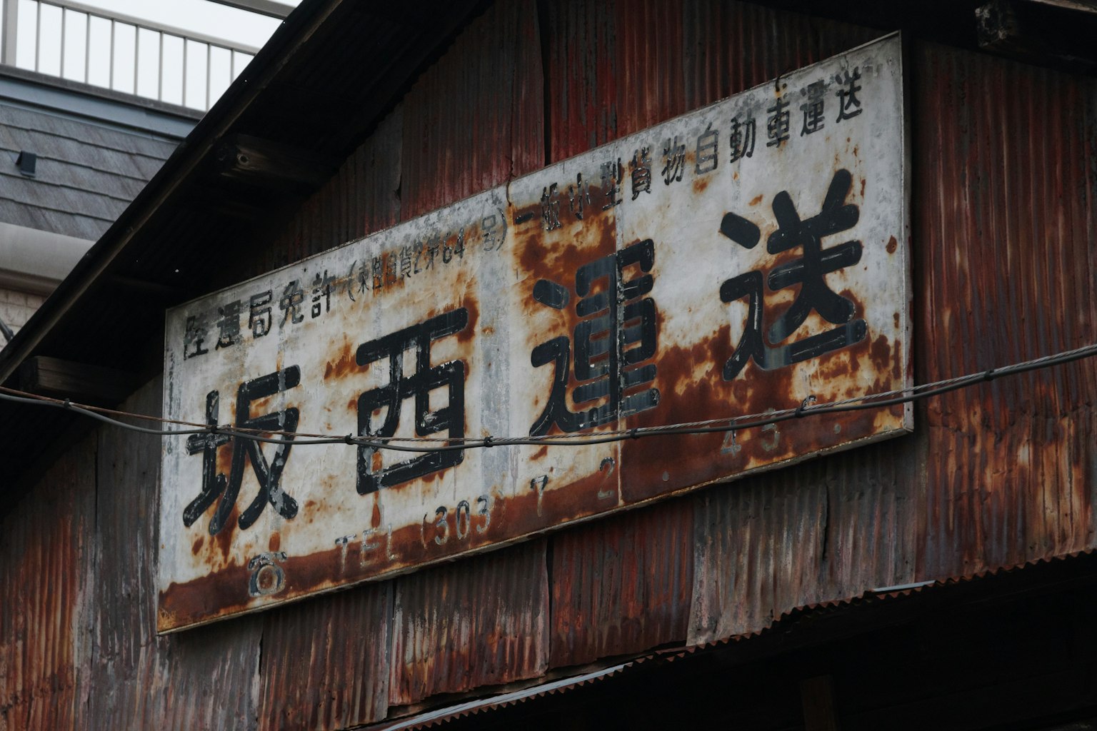 生鏽的標誌上有坂西運送字樣和風化的金屬質感