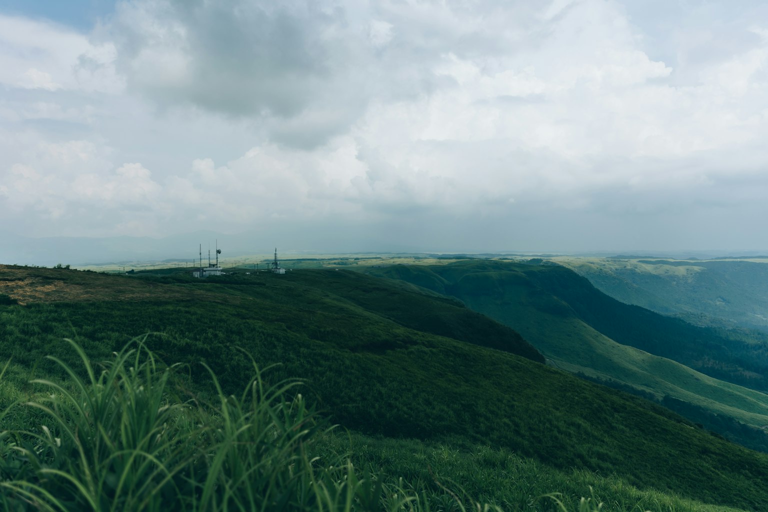 Scenic view of green hills under a cloudy sky